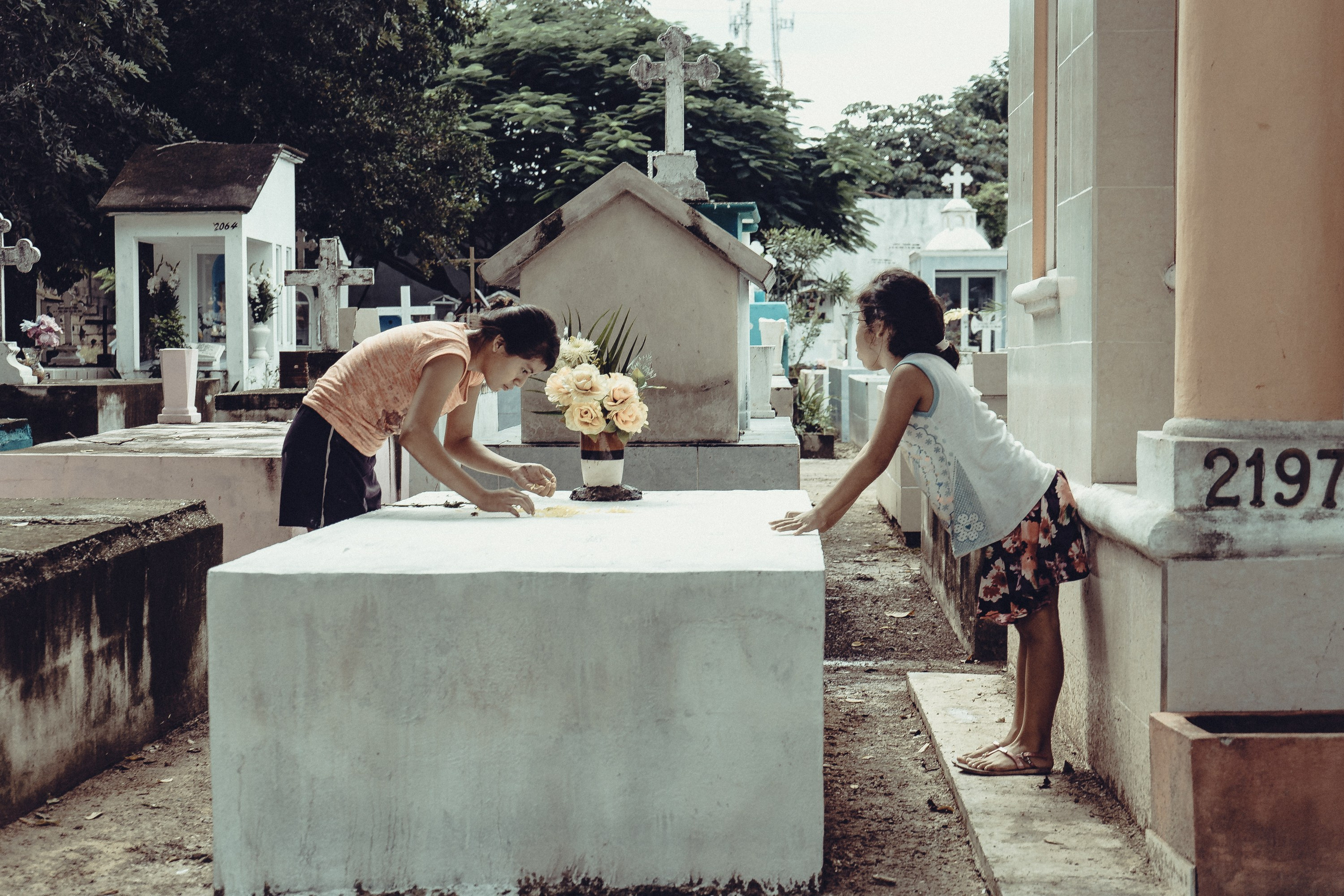 Девочка и мальчик на могиле в День Мёртвых.