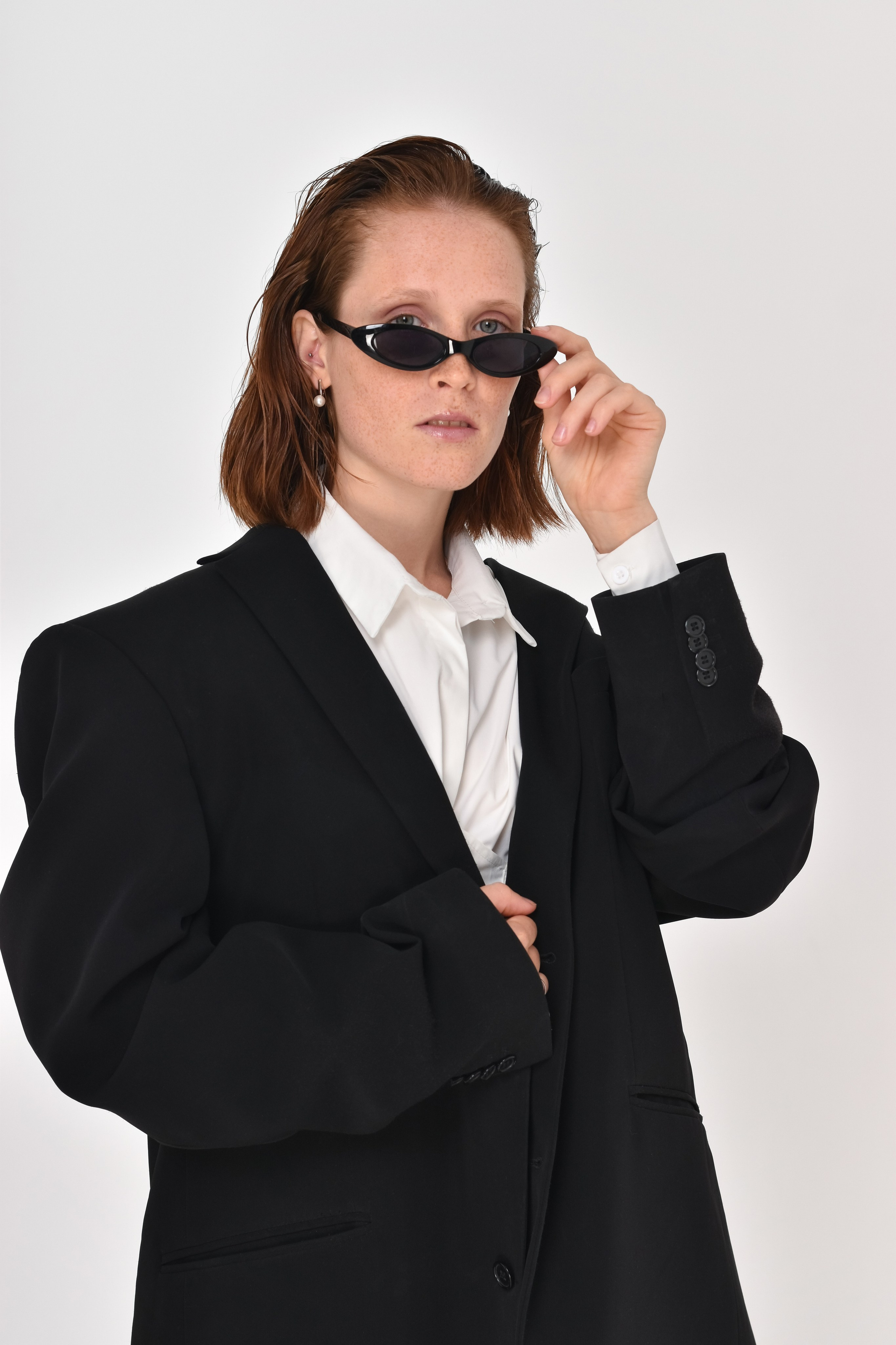 Рыжая девушка модель в большом черном пиджаке и солнечных очках