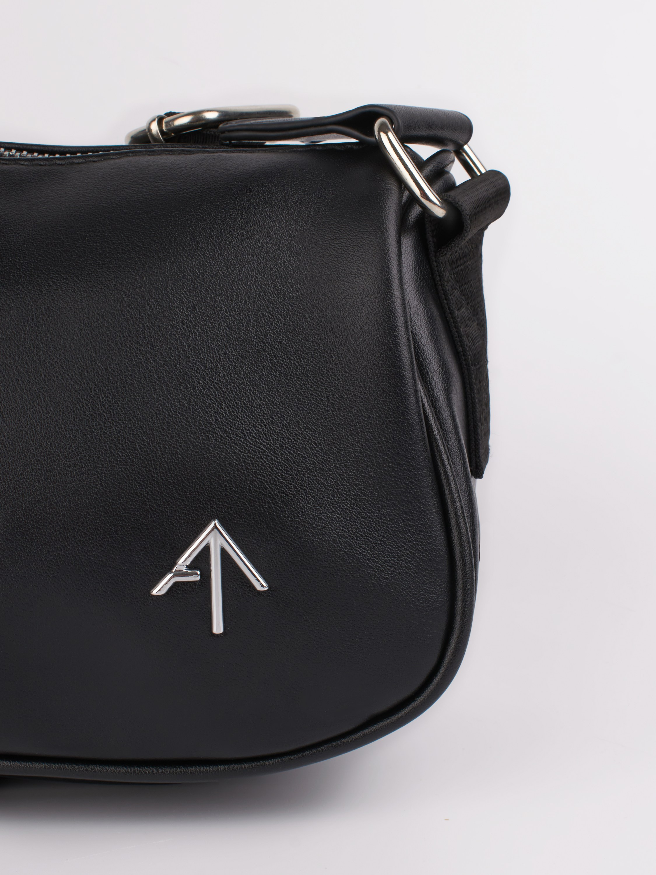 Деталь в виде стрелки на женской черной сумке крупным планом 