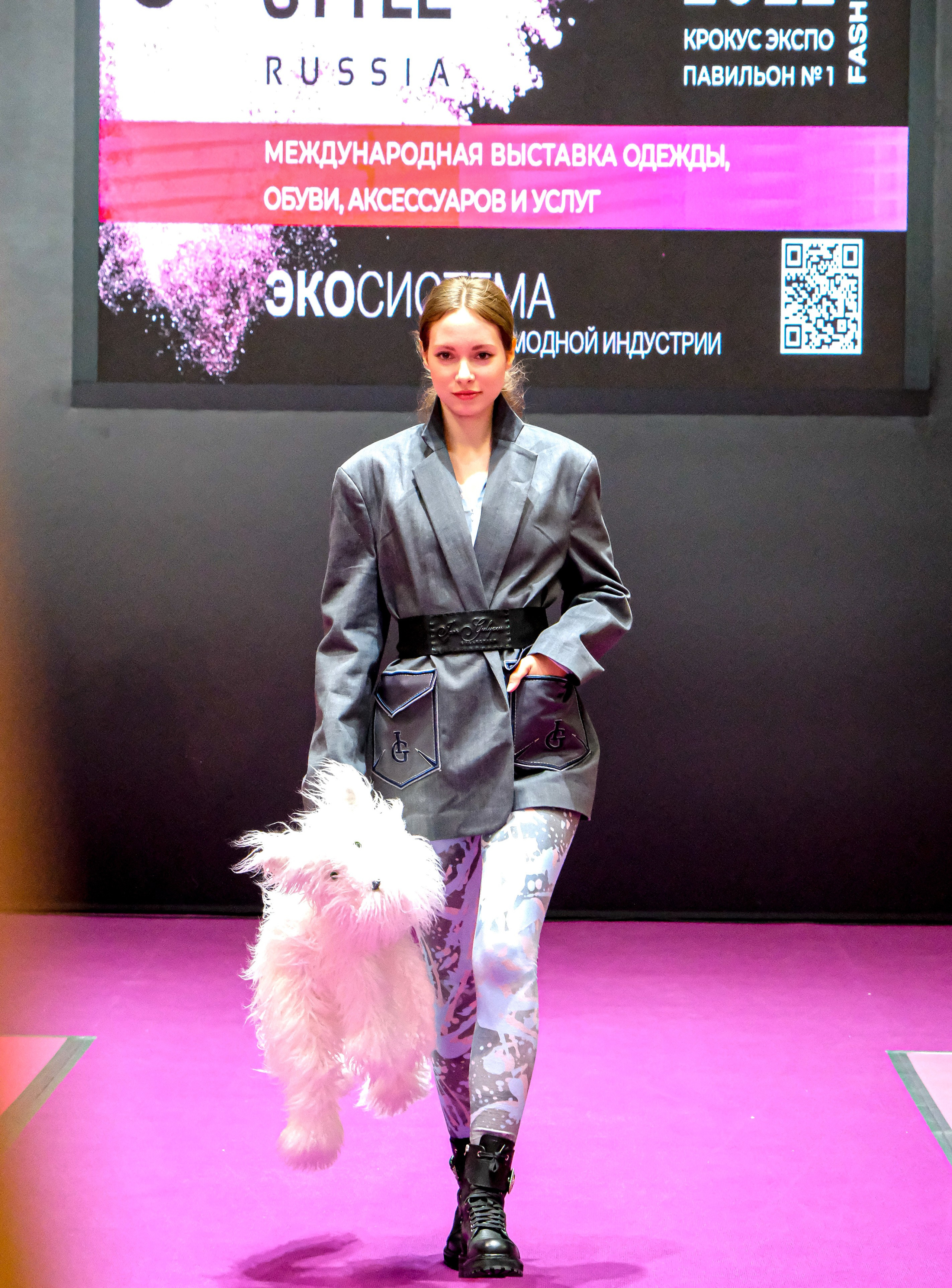  "Модели в ярких нарядах проходят по подиуму во время показа мод, освещенные яркими софитами и окруженные восторженными зрителями."