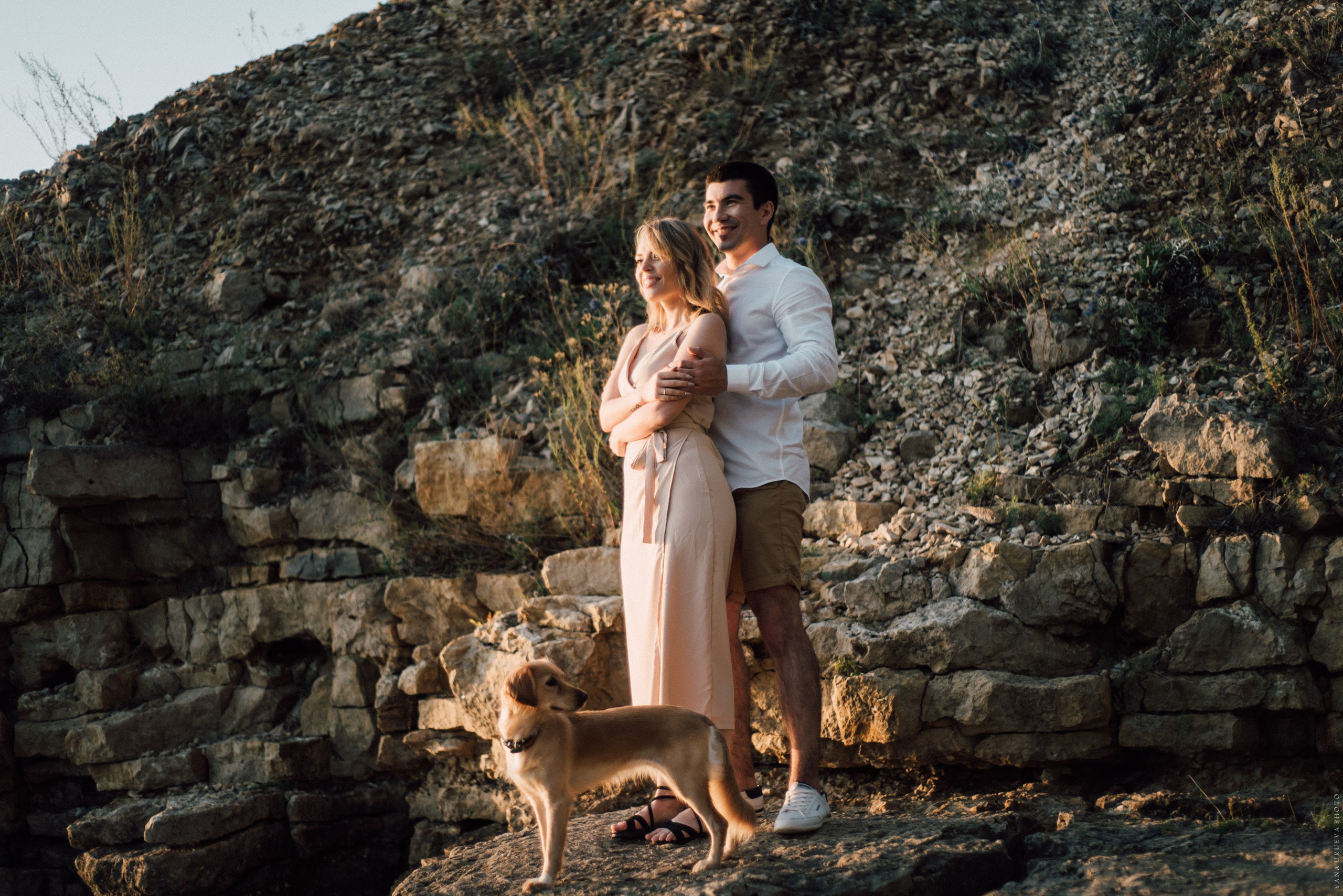 парень девушка и их осбака стоят на берегу на закате