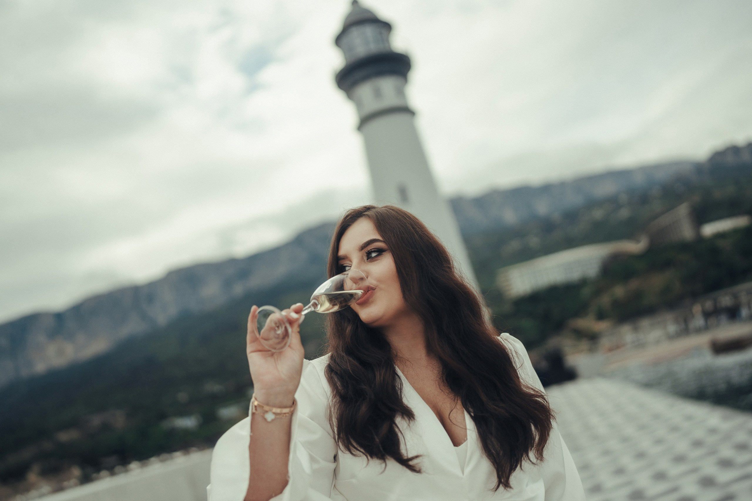Репортажная фотосессия в Крыму: девушка пьёт шампанское на фоне маяка на южном берегу Крыма, курорт "Мрия".