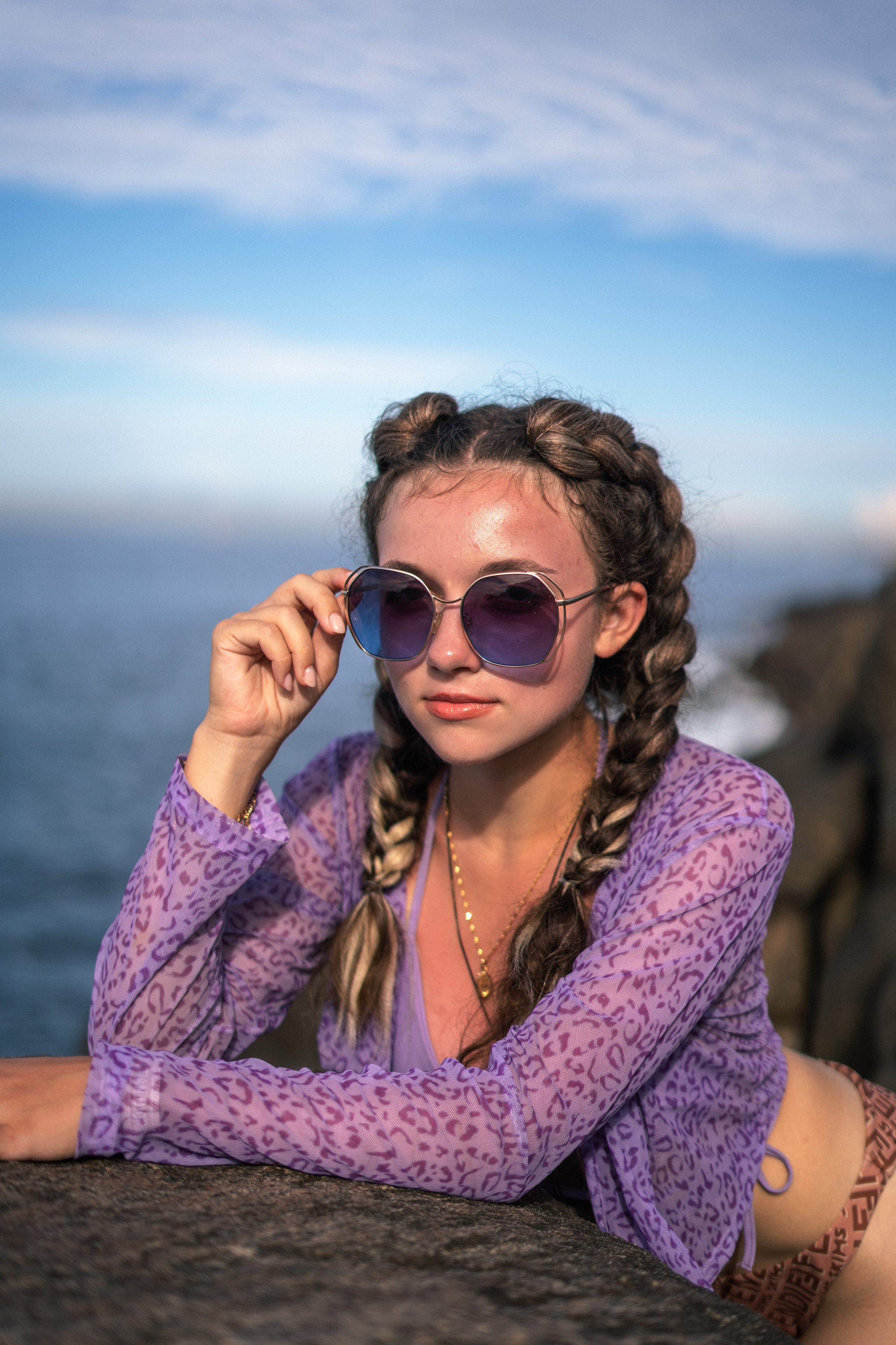 a young girl in a purple swimsuit enjoying the moment on the rocks