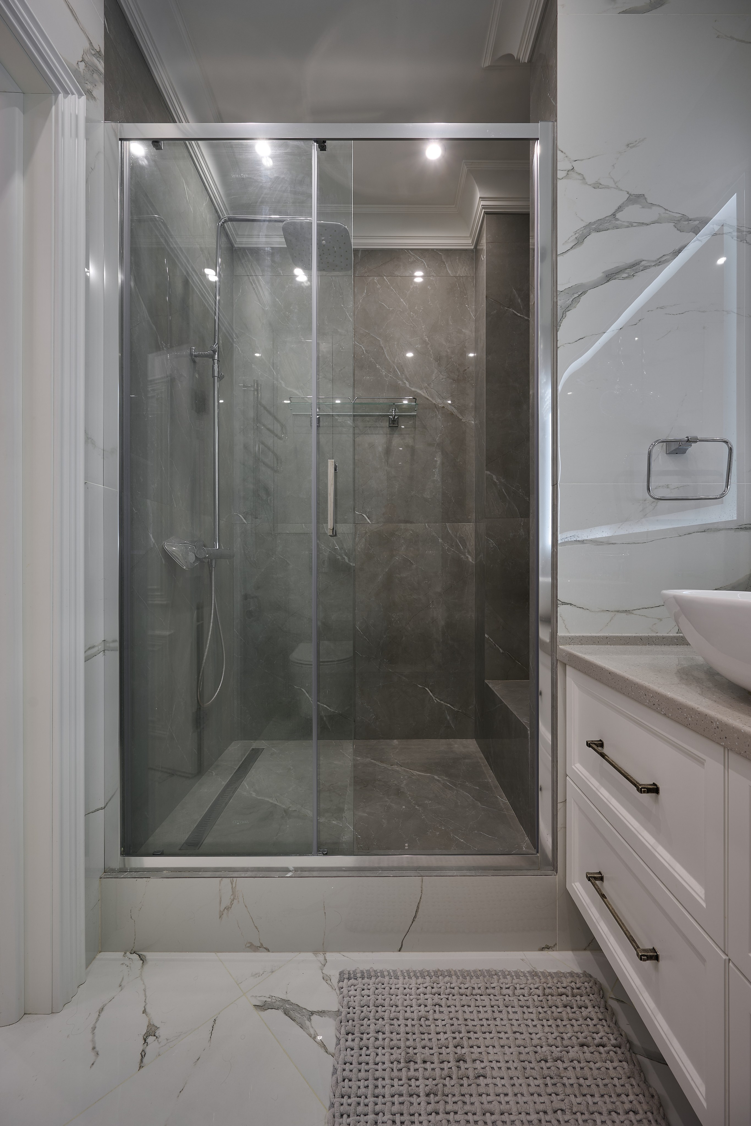 душевая кабинка с прозрачной стенкой и серыми обоями 