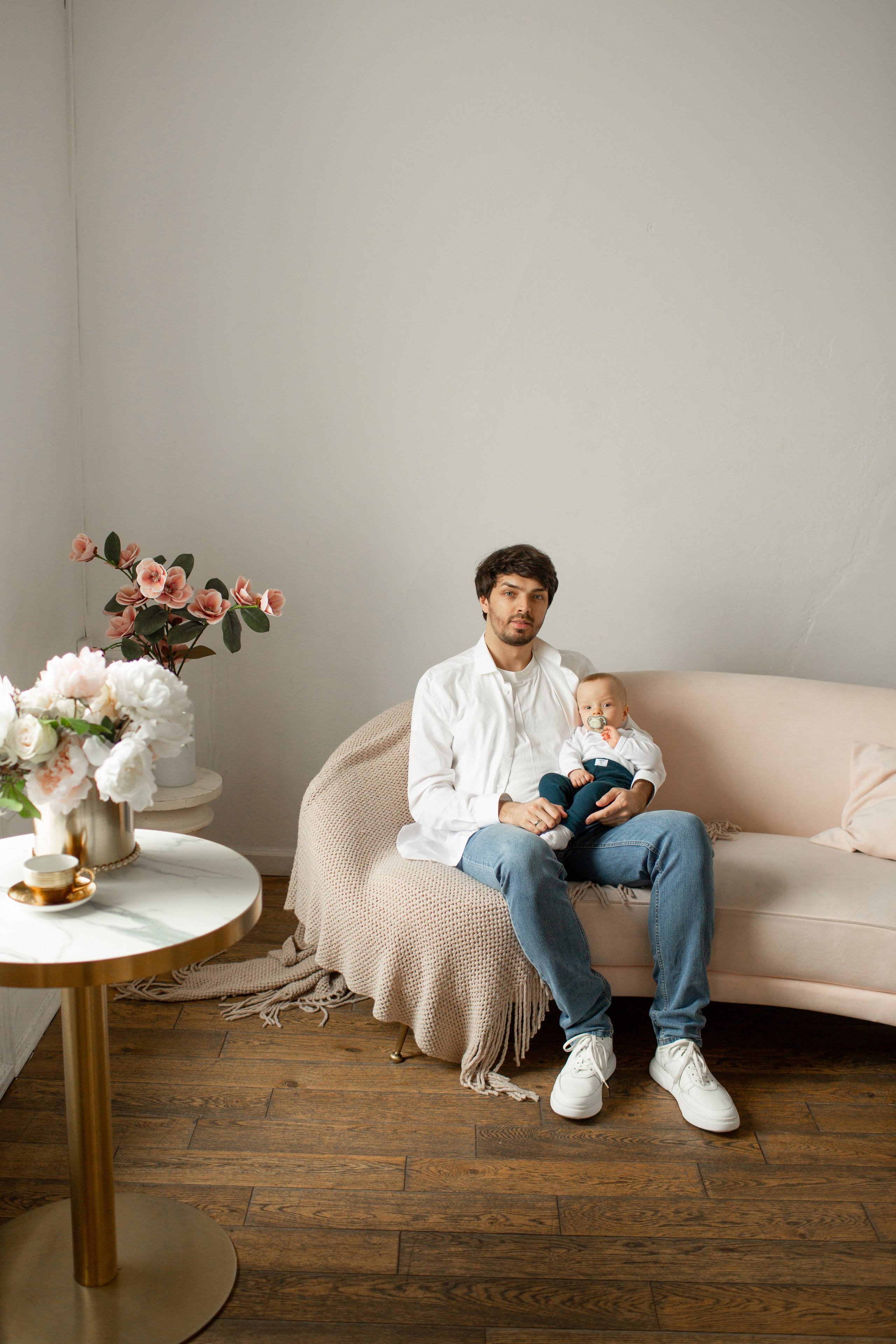 Семейная фотосессия в студии: папа с малышом сидит на диване.