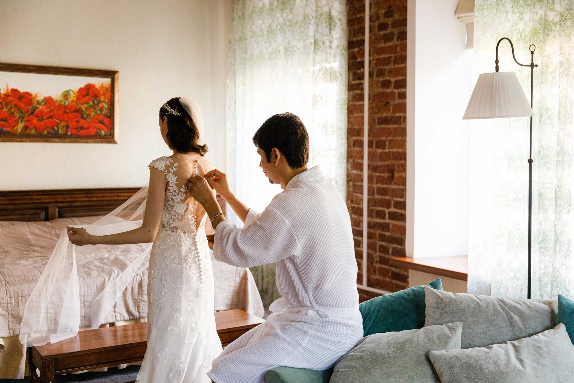 Жених застегивает платье невесте