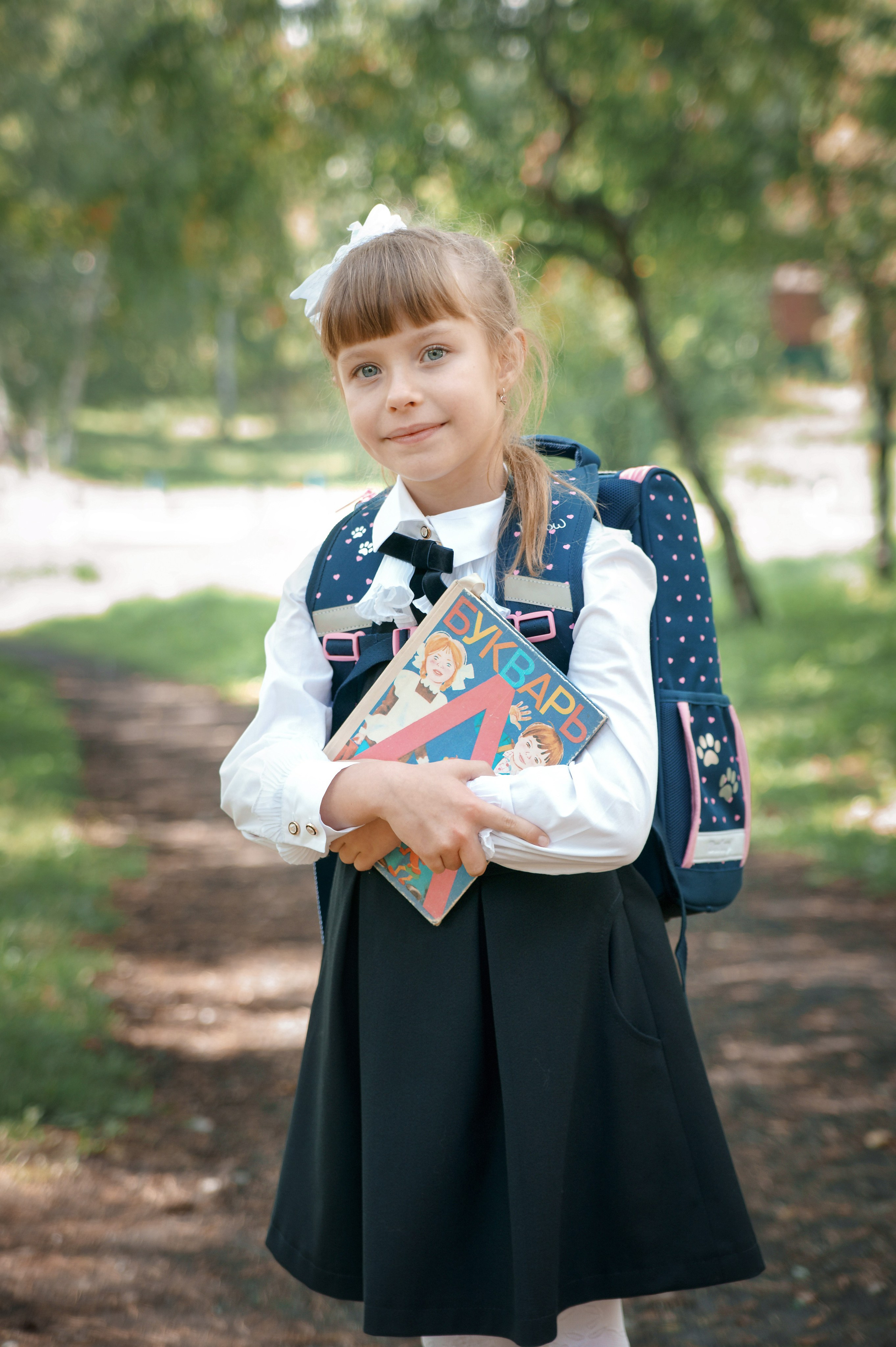 Детская фотосессия осенью - школьница стоя с учебником