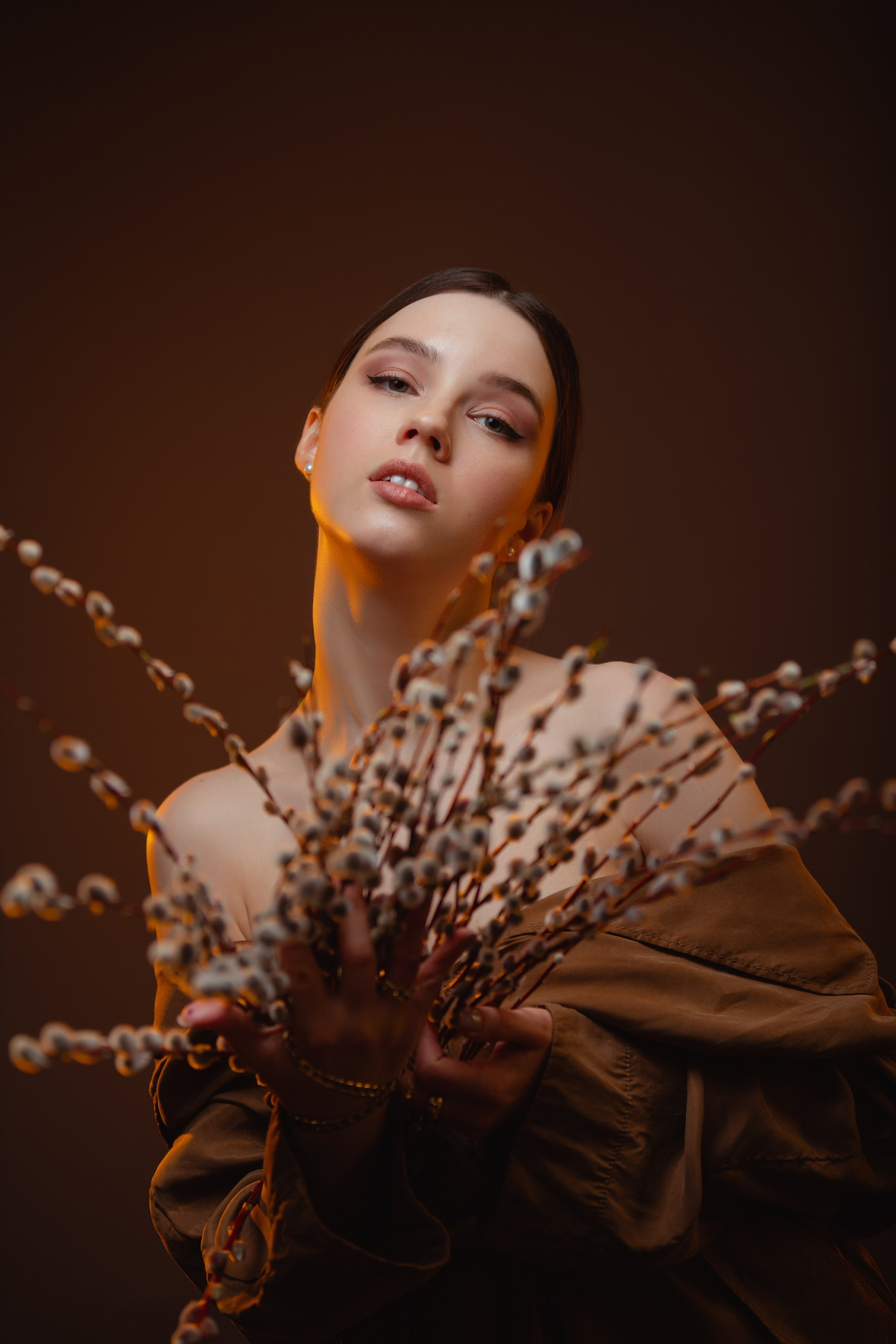 Девушка на коричневом фоне держит в руках букет  вербы