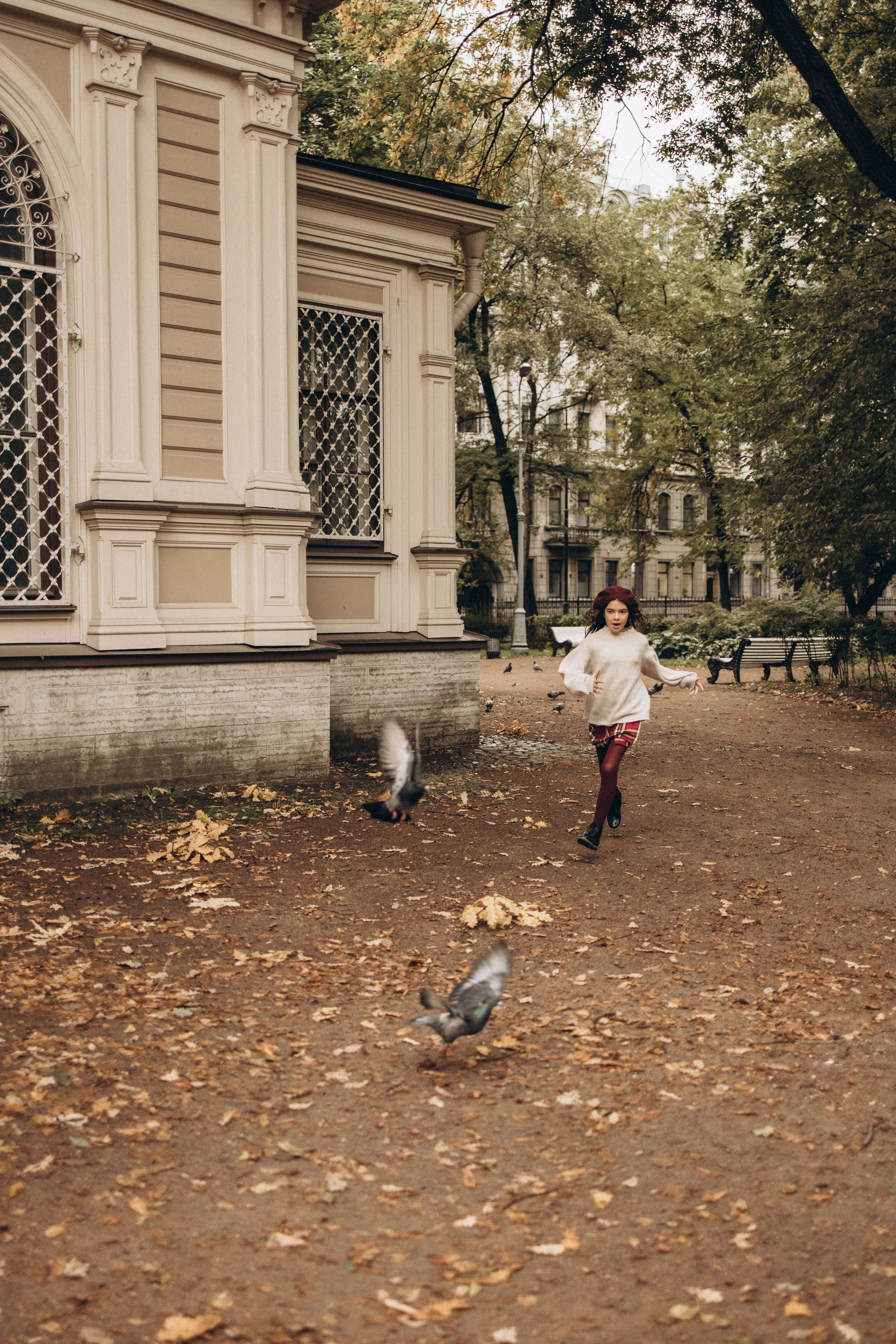 девочка радостно гоняет голубей по парку