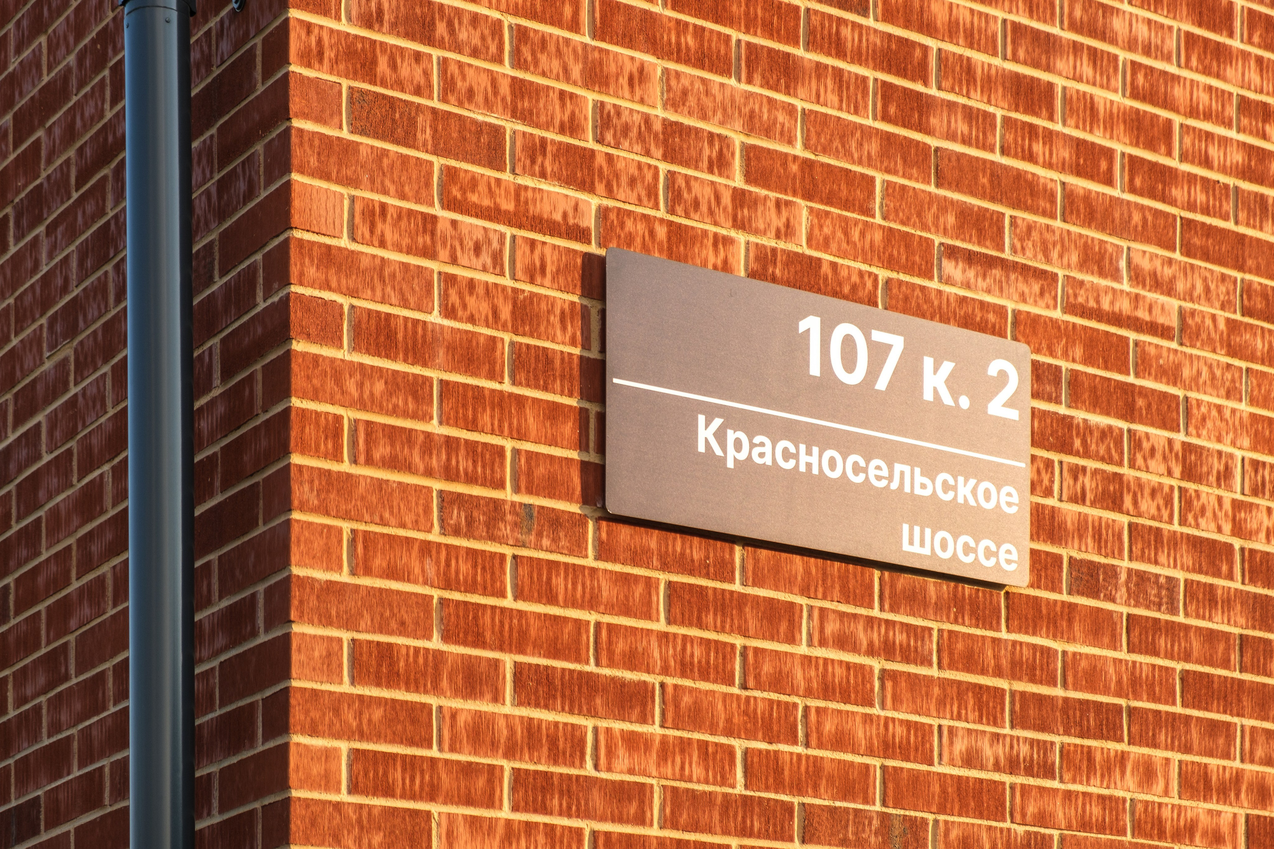 Кирпичный дом. На стене прикреплена табличка с надписью "107 к. 2".