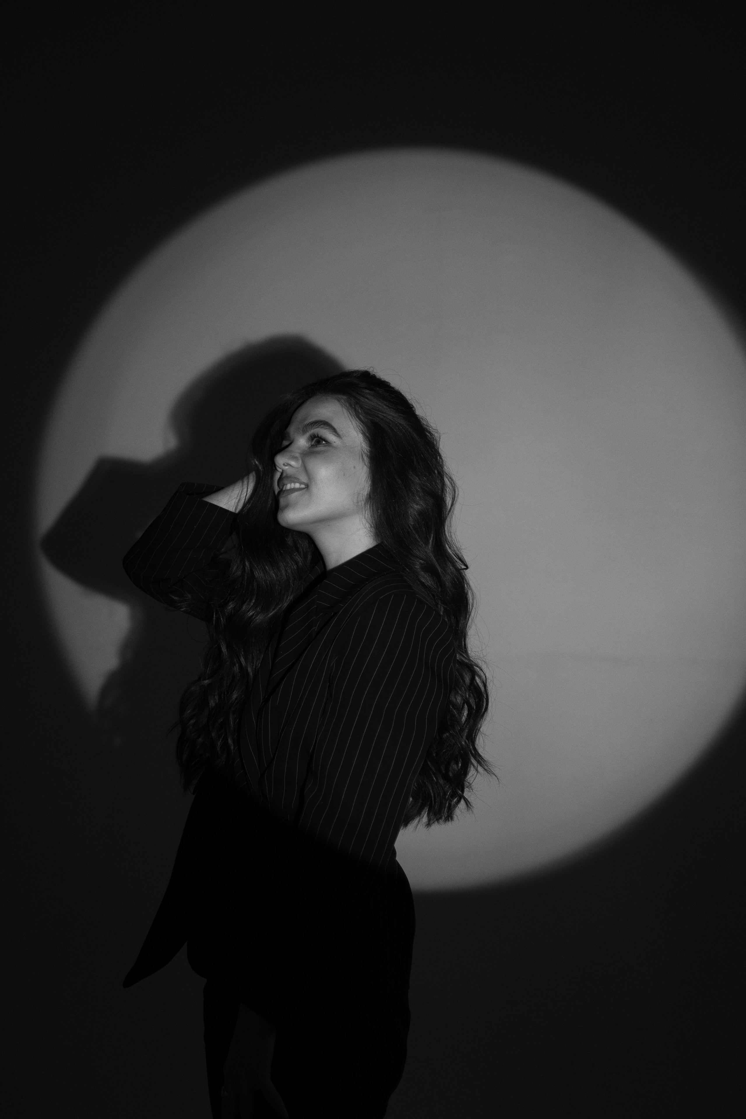 поза красивой девушки на фоне маски гобо в студии в черном костюме