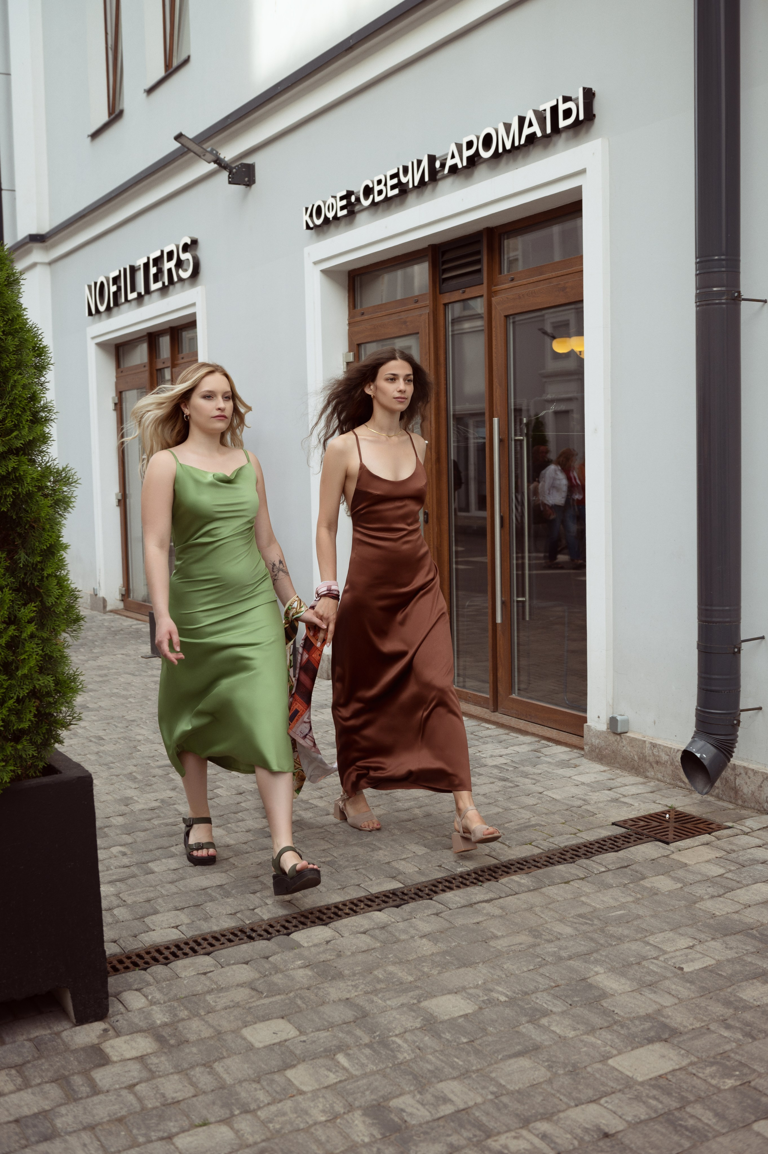 Две девушки, блондинка и брюнетка идут по улице, взявшись за руки