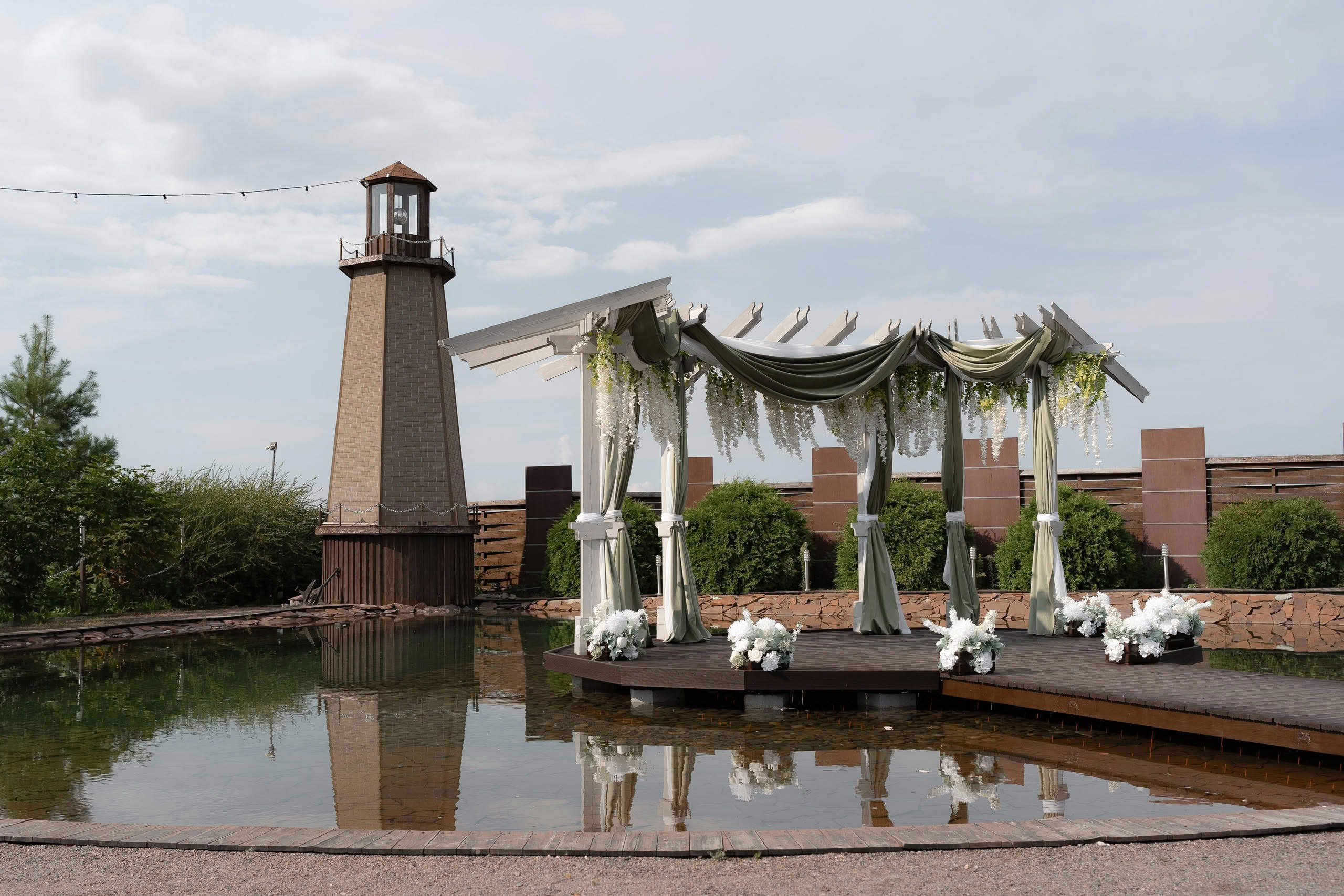 Зона свадебной церемонии у воды с аркой и маяком — подготовка пространства