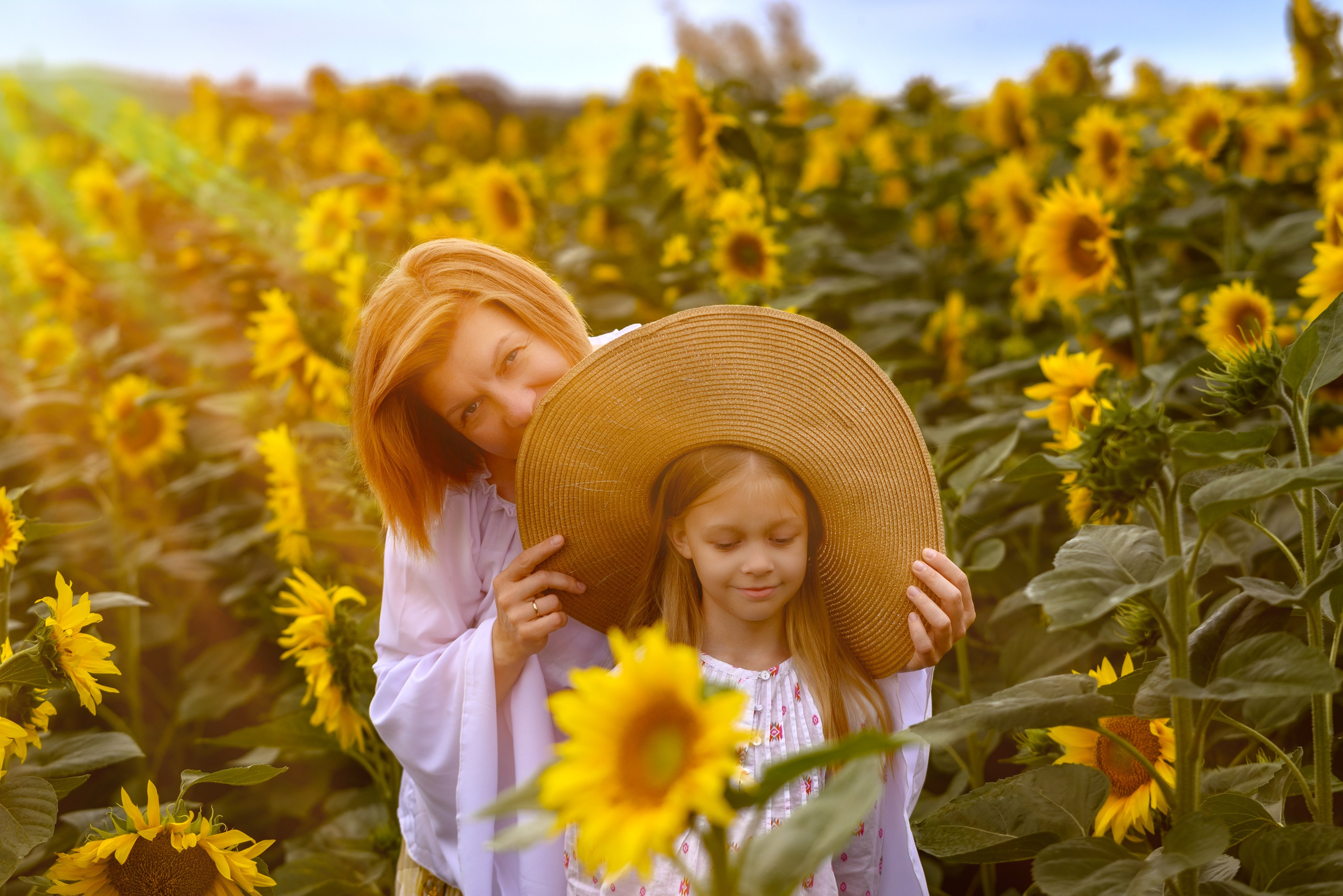 Детская фотосъемка на природе — девочка в шляпе и мама среди подсолнухов