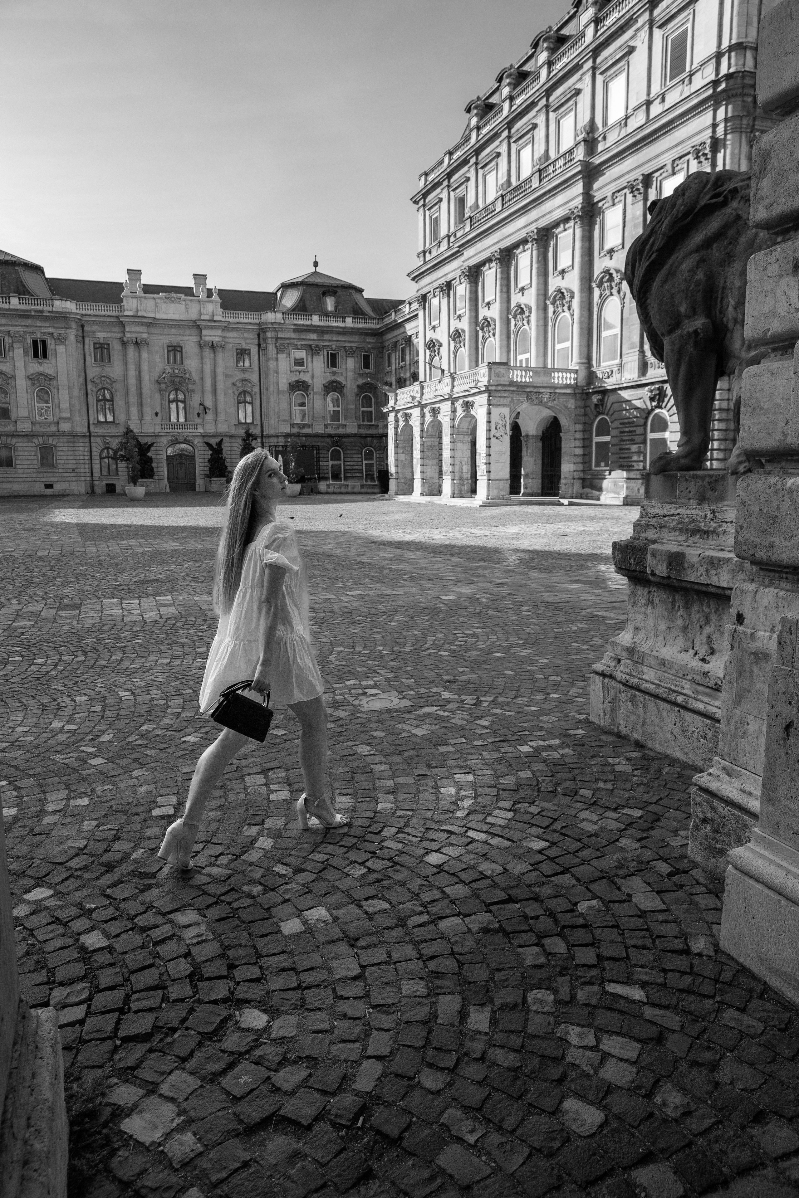 black and white photo of a girl in a white dress walking around Buda Castle
