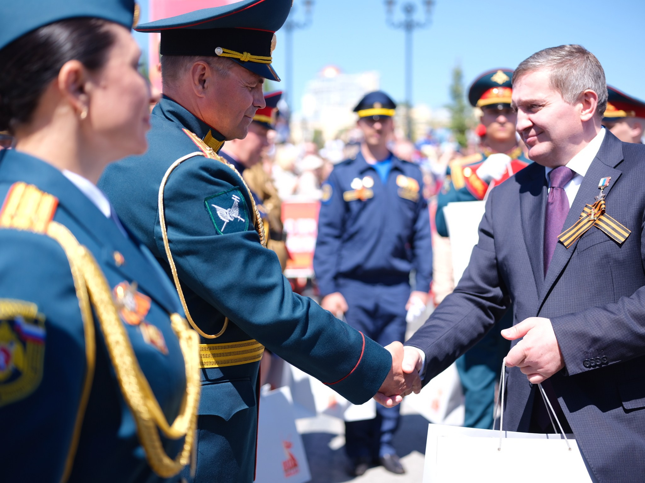 Девочки-кадеты в белых беретах и форме несут портреты героев фронта в ходе «Бессмертного полка» по главной улице города