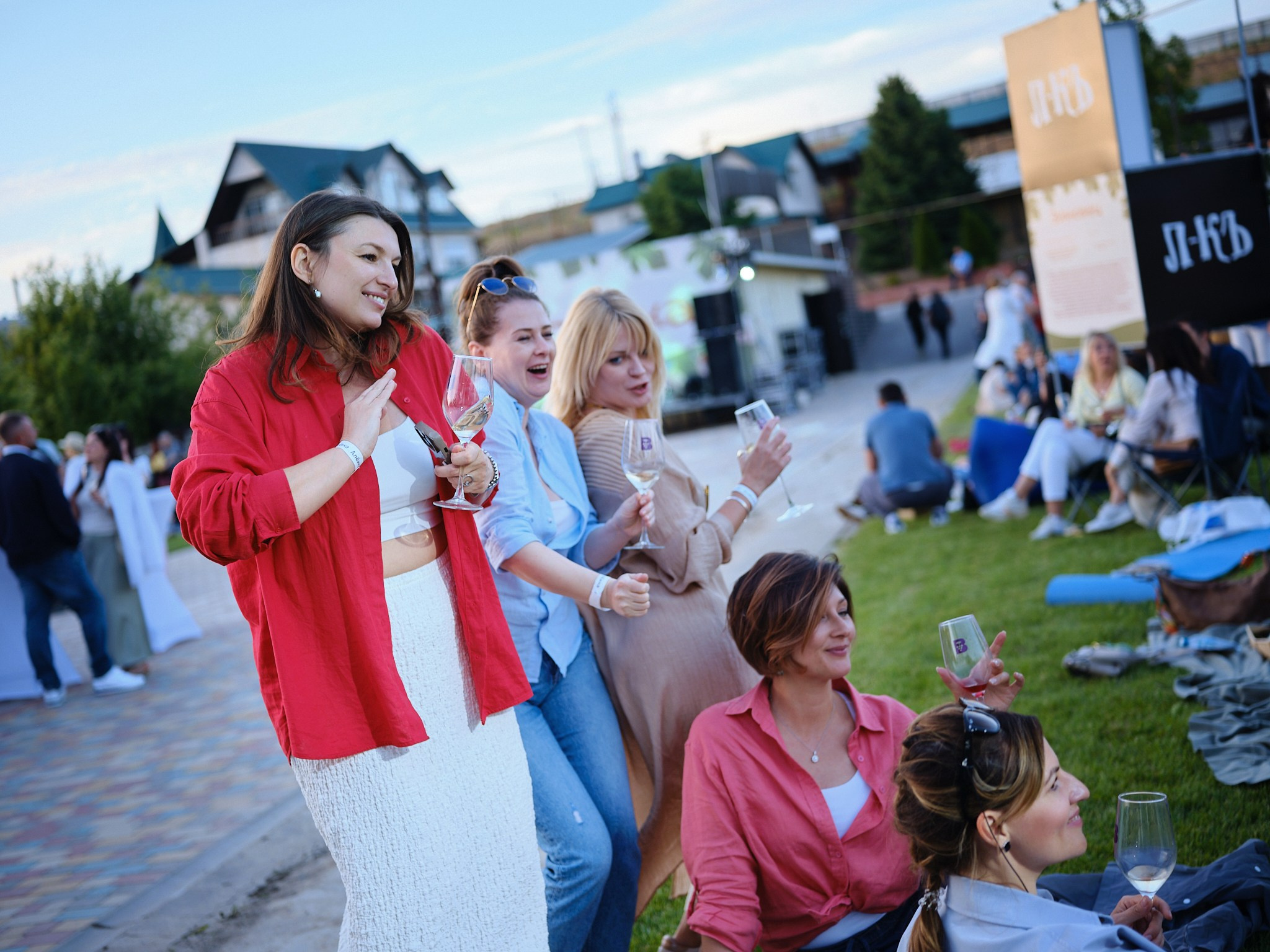 Сомелье в фартуке разливает белое вино из бутылки в стеклянный бокал на ярмарке винных традиций