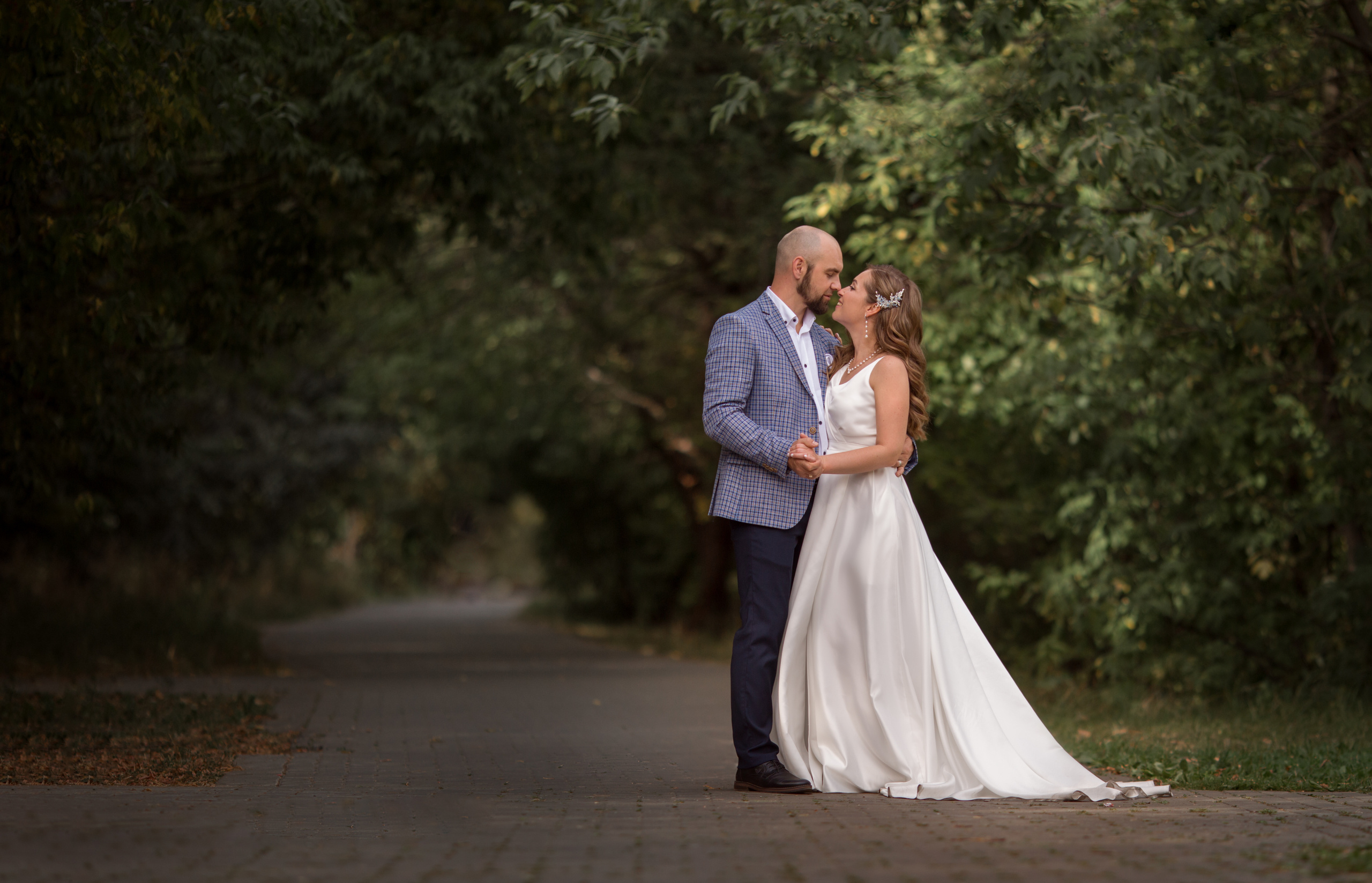 жених и невеста стоят на фоне зеленой рощи в измайловском парке