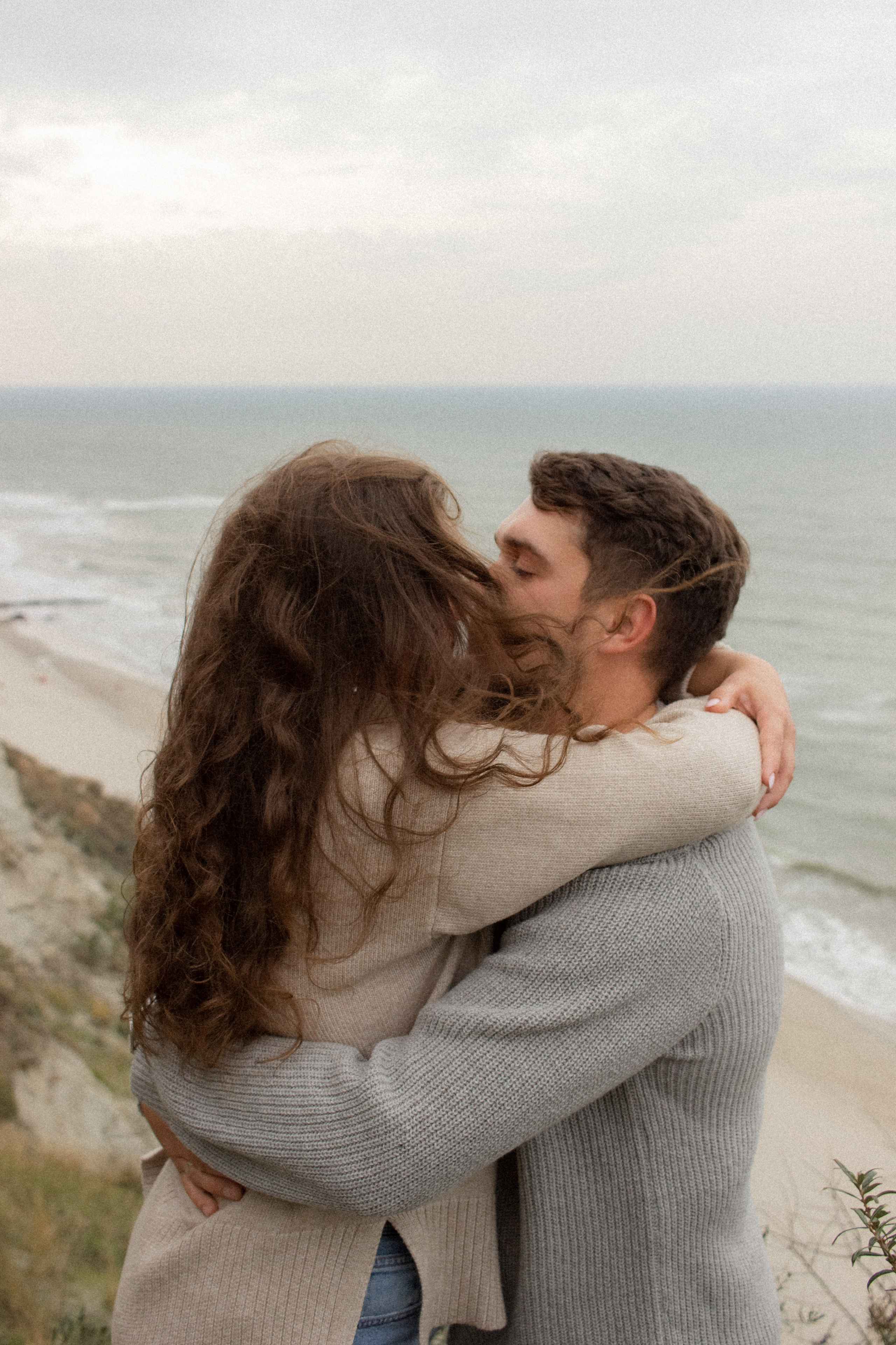 Влюбленная пара целуется на фоне обрыва и море