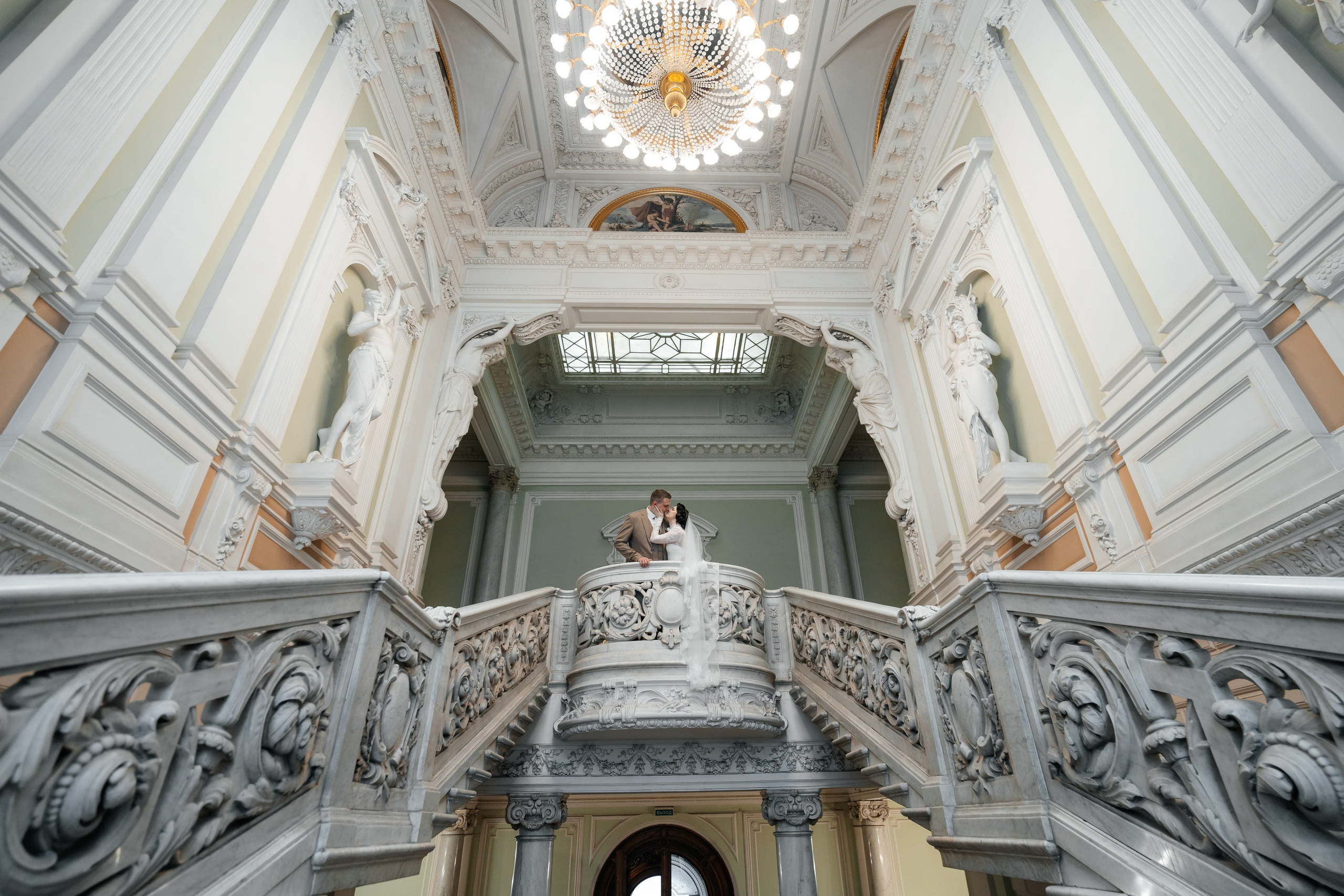 Свадебная фотосессия во Дворце Бракосочетания №1 Жених и невеста стоят на балконе лестницы.