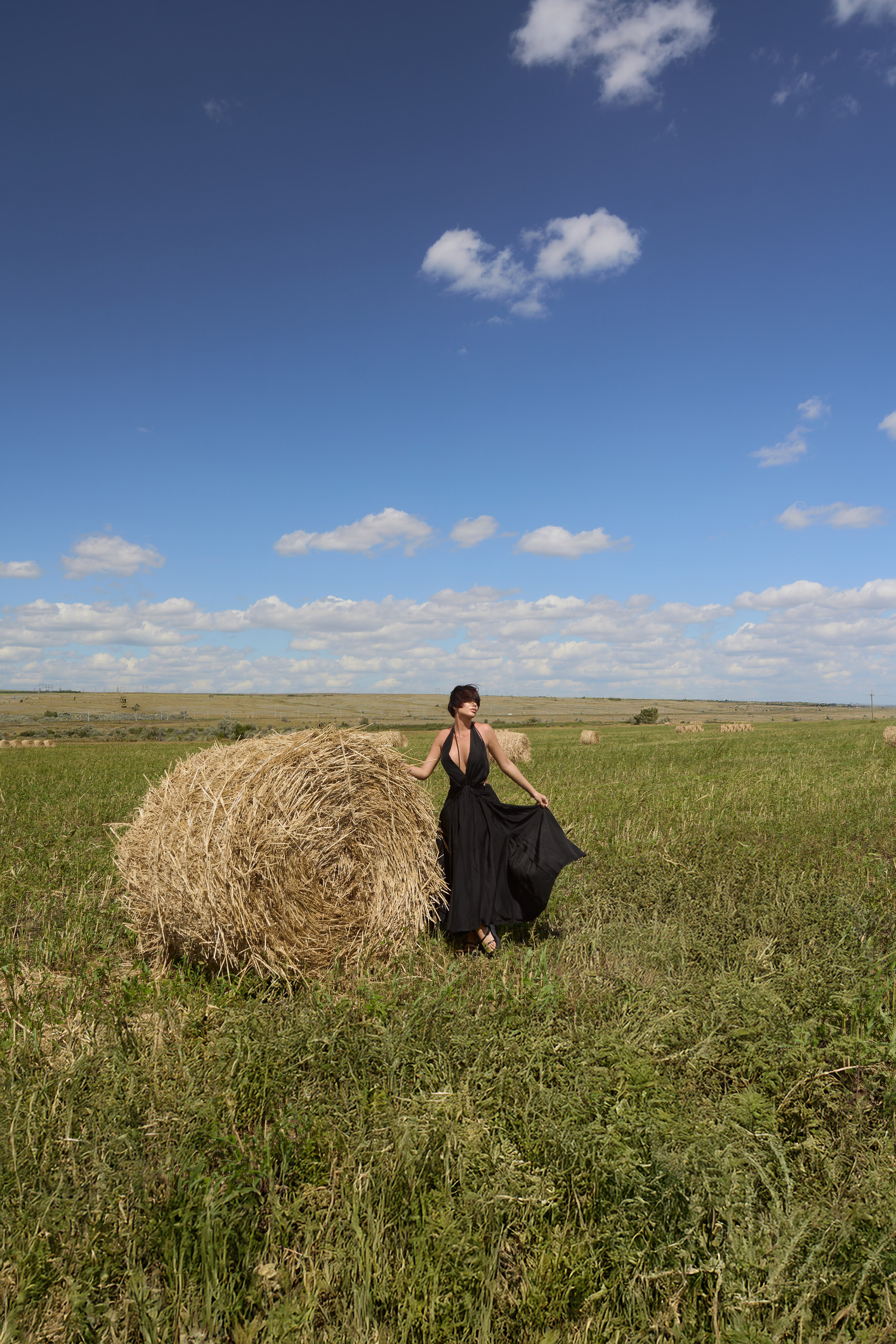 На этом фото с прогулочной фотосессии прекрасная девушка в развевающемся черном платье. Снято в полях Саратова со стогами сена. Фотограф Саратов - Москва