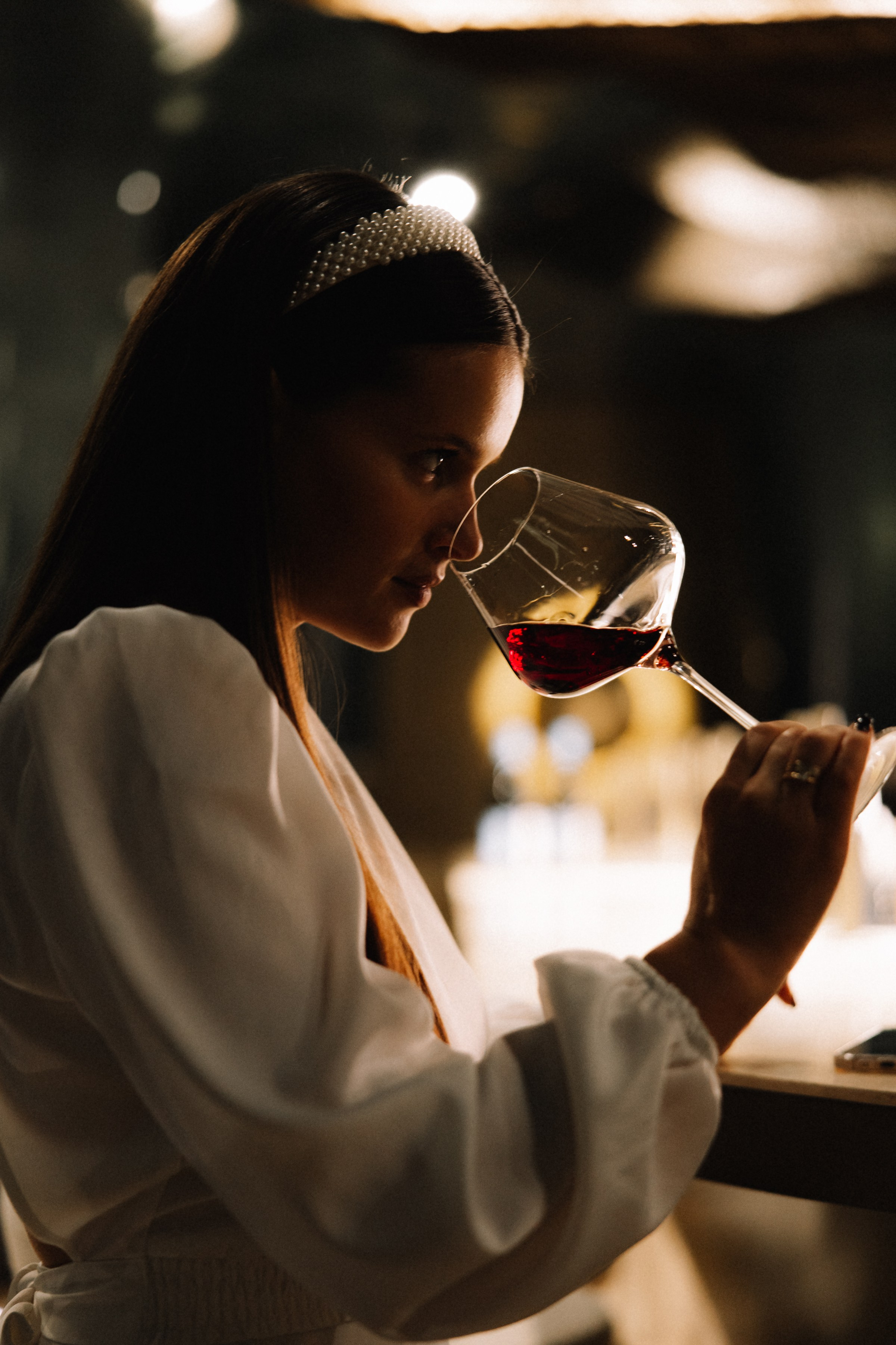 Дегустация: Крупный план гостьи, оценивающей аромат красного вина в бокале.