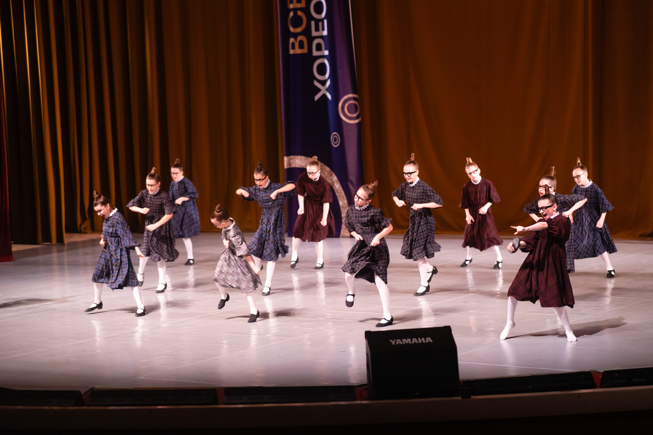 Широкий кадр с быстрым перемещением линий танцоров с одного края сцены на другой.