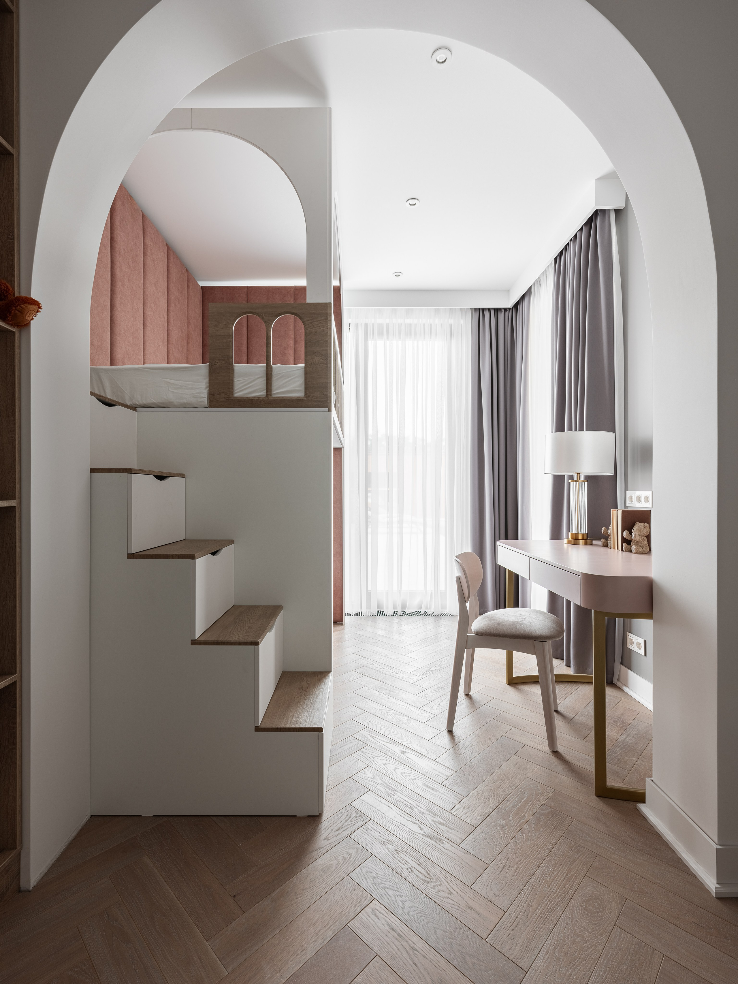 Современная детская с арочными архитектурными элементами, белой лестницей с ящиками, кроватью с мягким розовым изголовьем и большим окном с серыми шторами, созданная дизайнером Василиссой Бачевой, стилистом Натальей Якушевой и снятая фотографом Сергеем Денисенко.