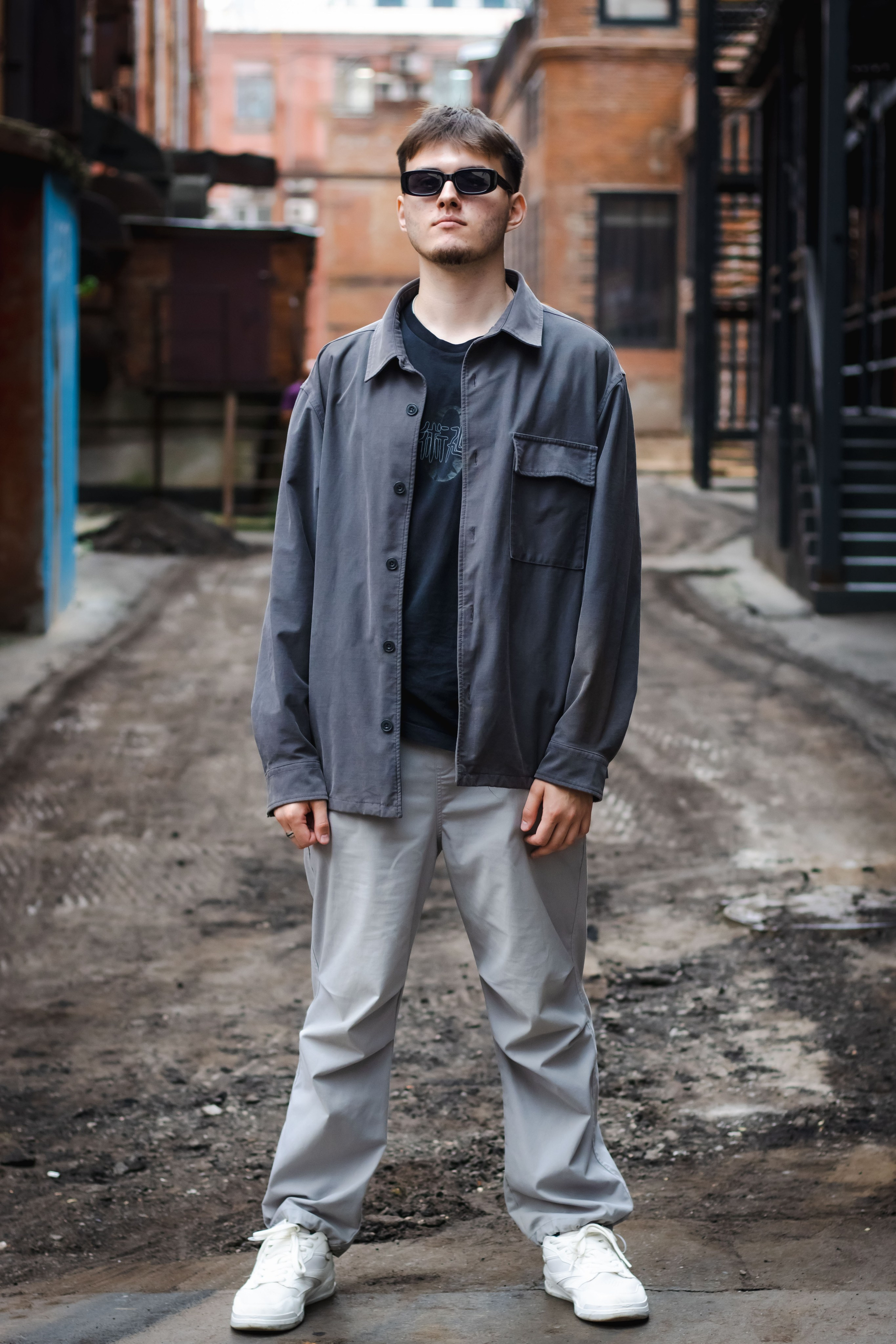 парень стоит на дороге без асфальта, виднеется грязь от шин 