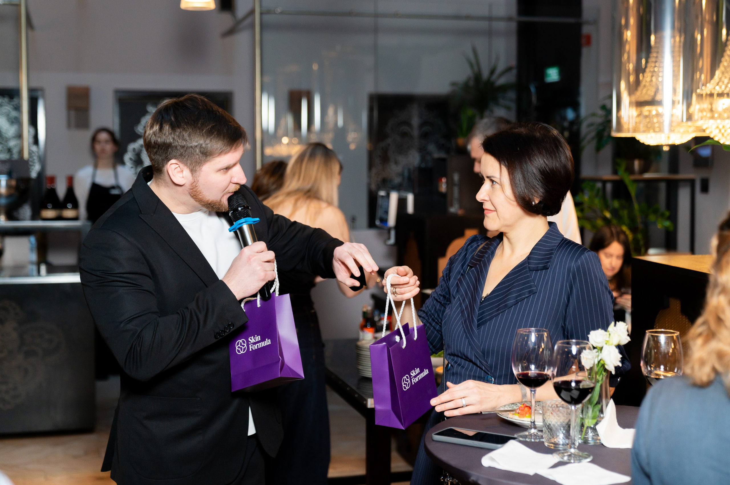Ведущий с микрофоном вручает подарочный пакет Skin Formula женщине. Фото Евгения Мальцева, Radisson Sonya Hotel.
