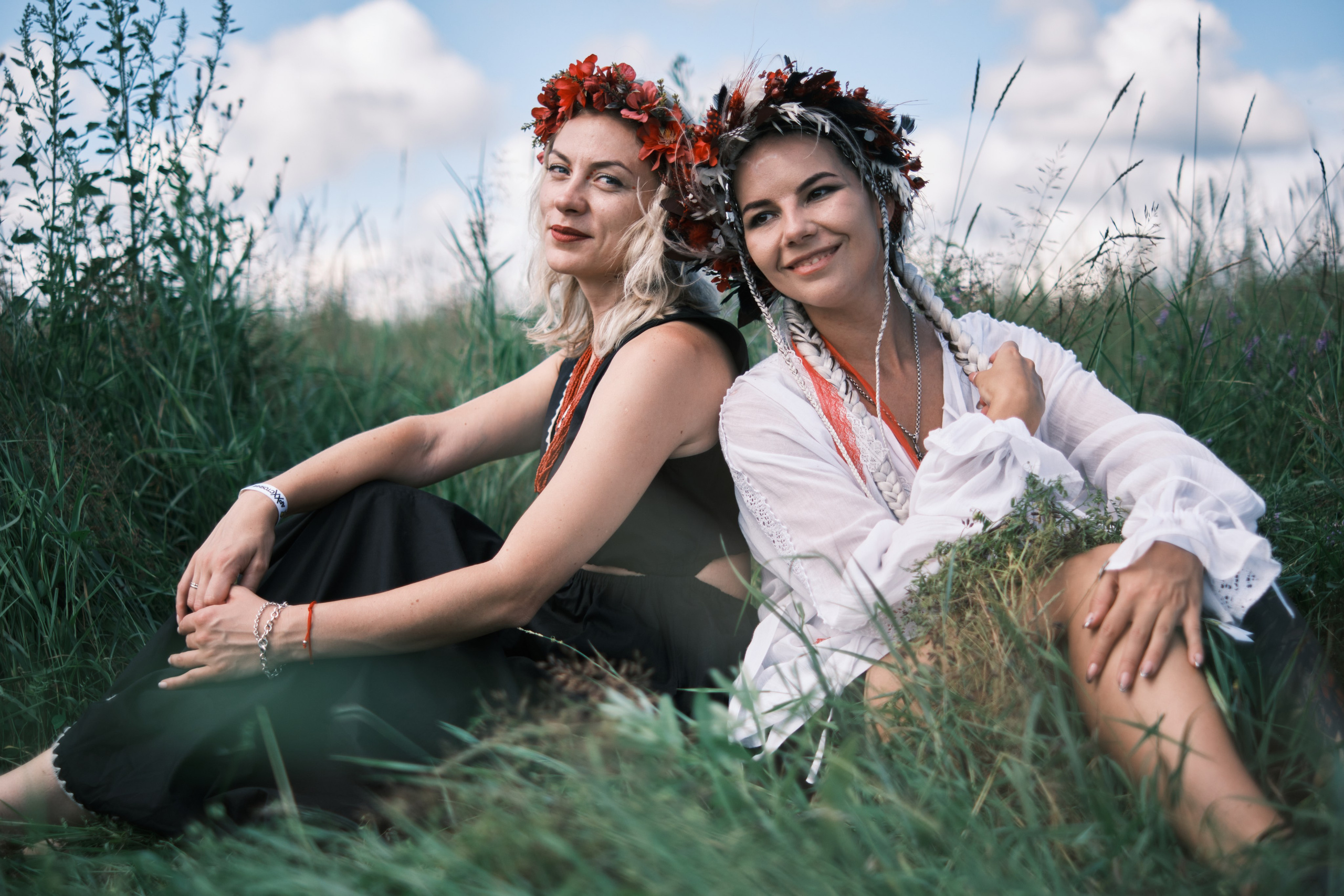 Девушки сидят спина к спине с венками на голове