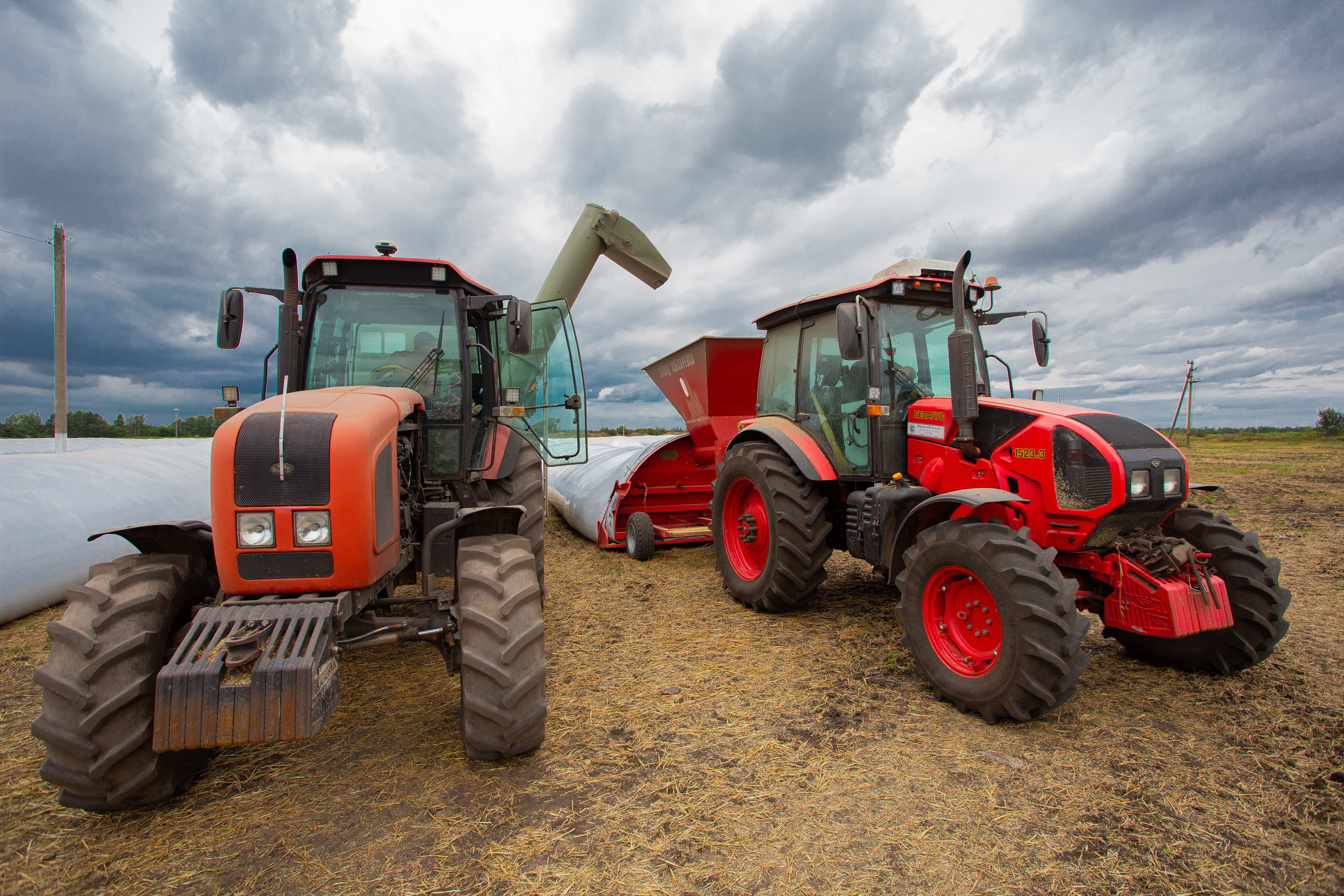 Сельскохозяйственная техника на уборке урожая и загрузке ячменя в рукава для хранения зерна 