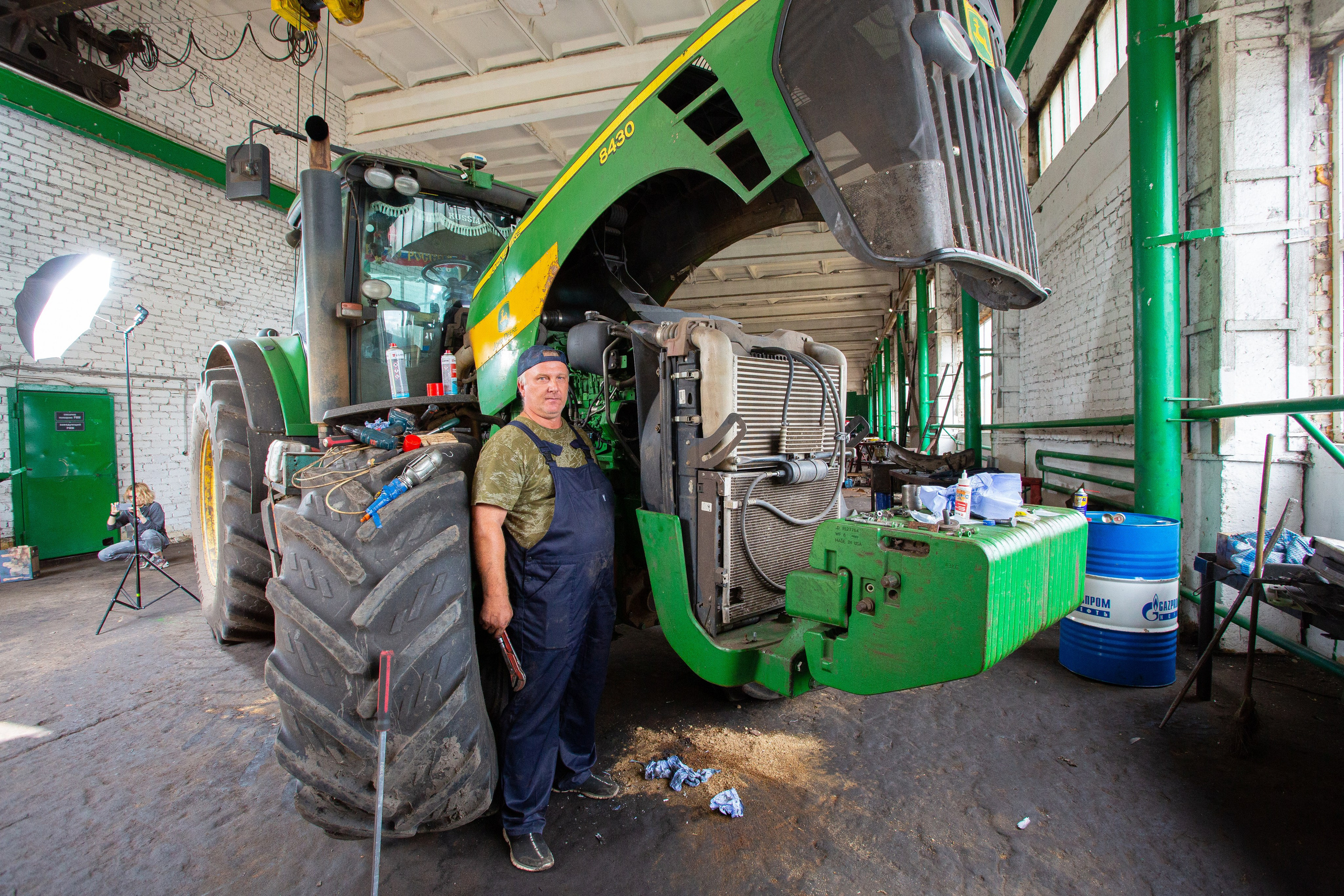 Слесарь-авторемонтник на фоне зеленого трактора