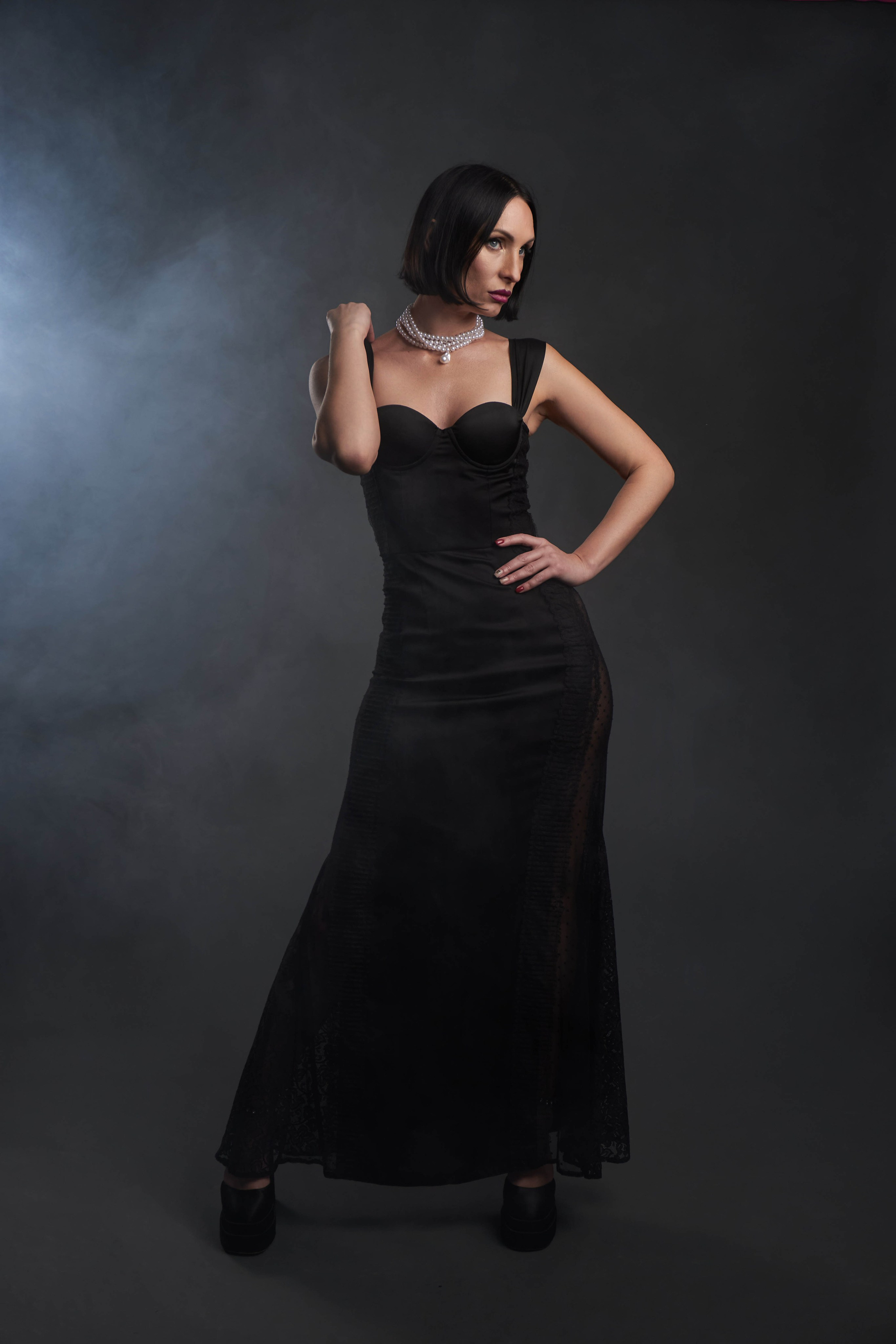 Женщина в длинном черном платье в студии с дымом