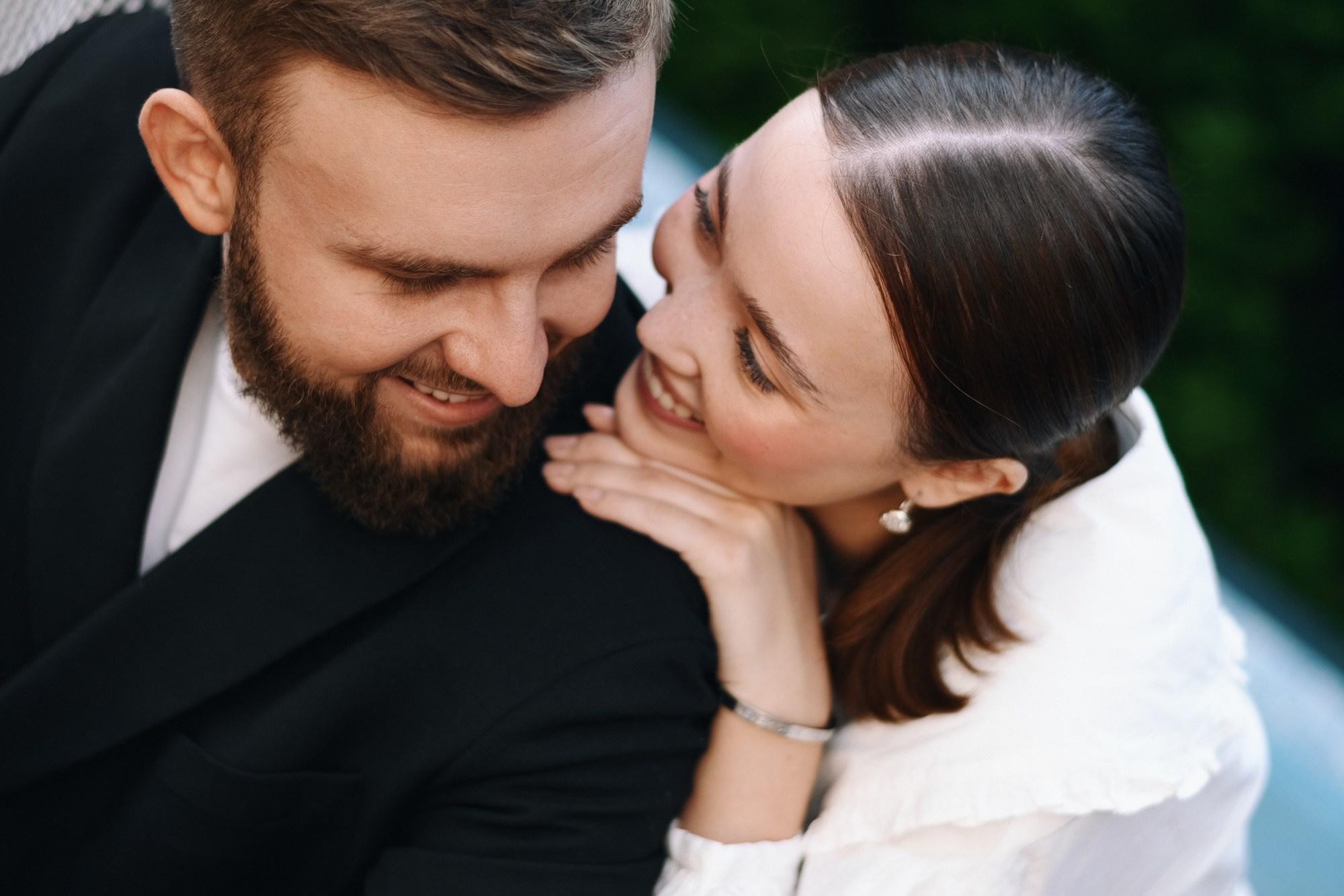 Крупный план смеющихся молодоженов на фоне яблоневого сада, искренние эмоции на свадьбе