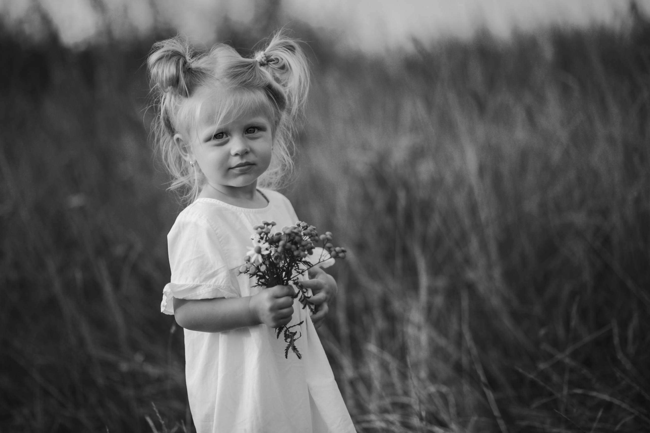 Little girl standing in tall grass and smiling