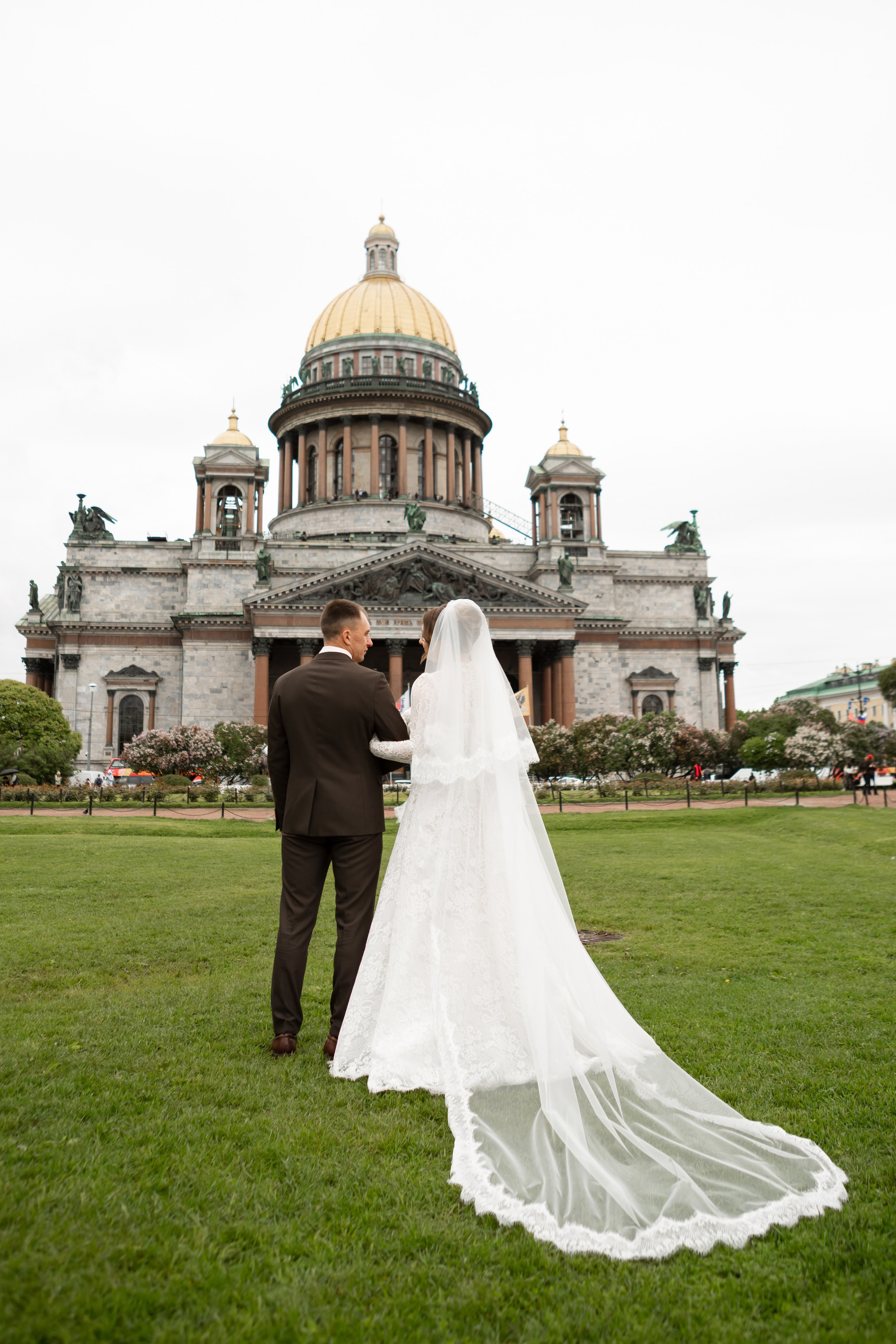 Молодожены фотографируются на лужайке перед Исаакиевским собором.