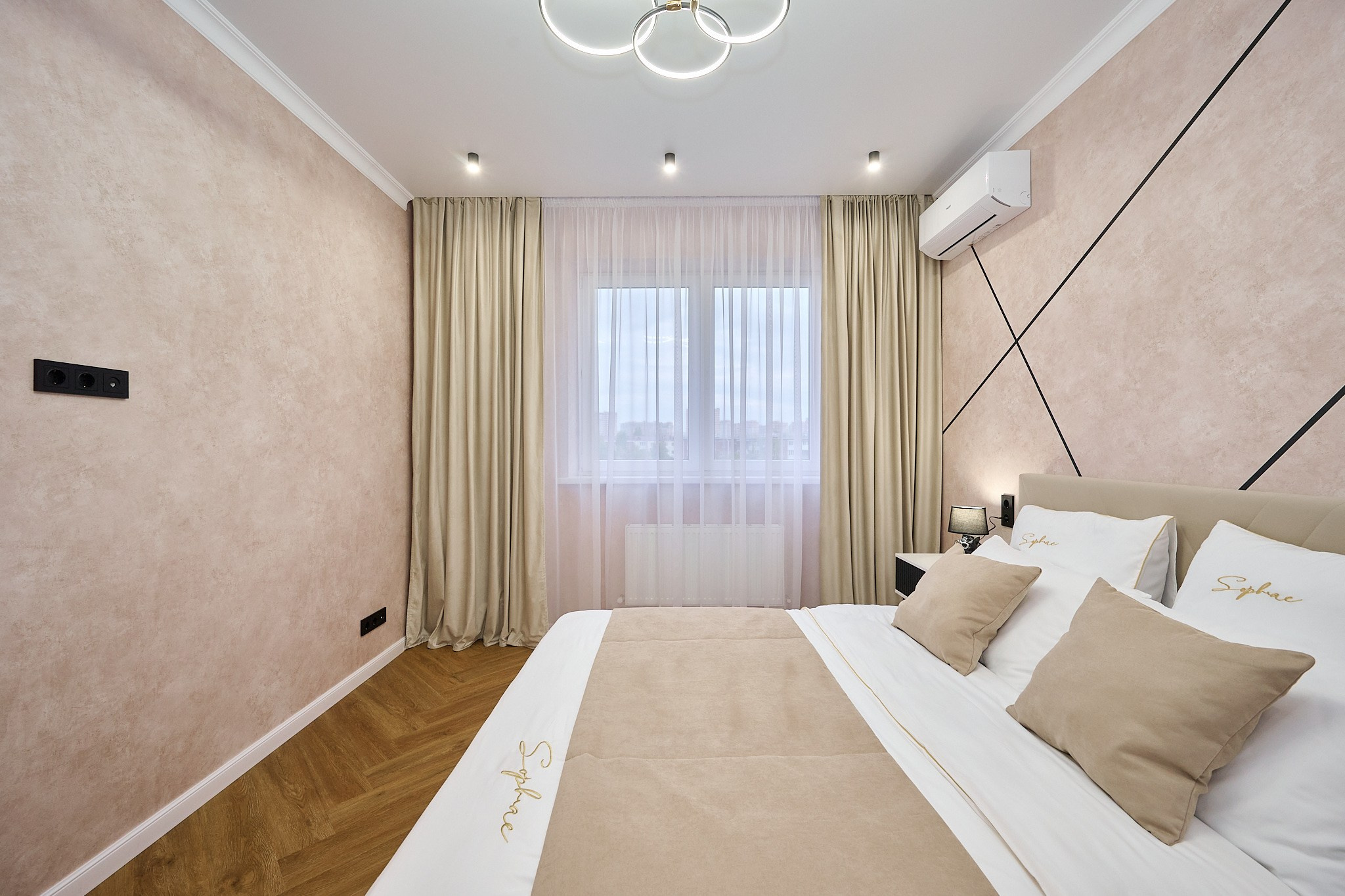 комната в светлых оттенках белые шторы коричневый ламинат бежевая кровать белые полки у кровати 