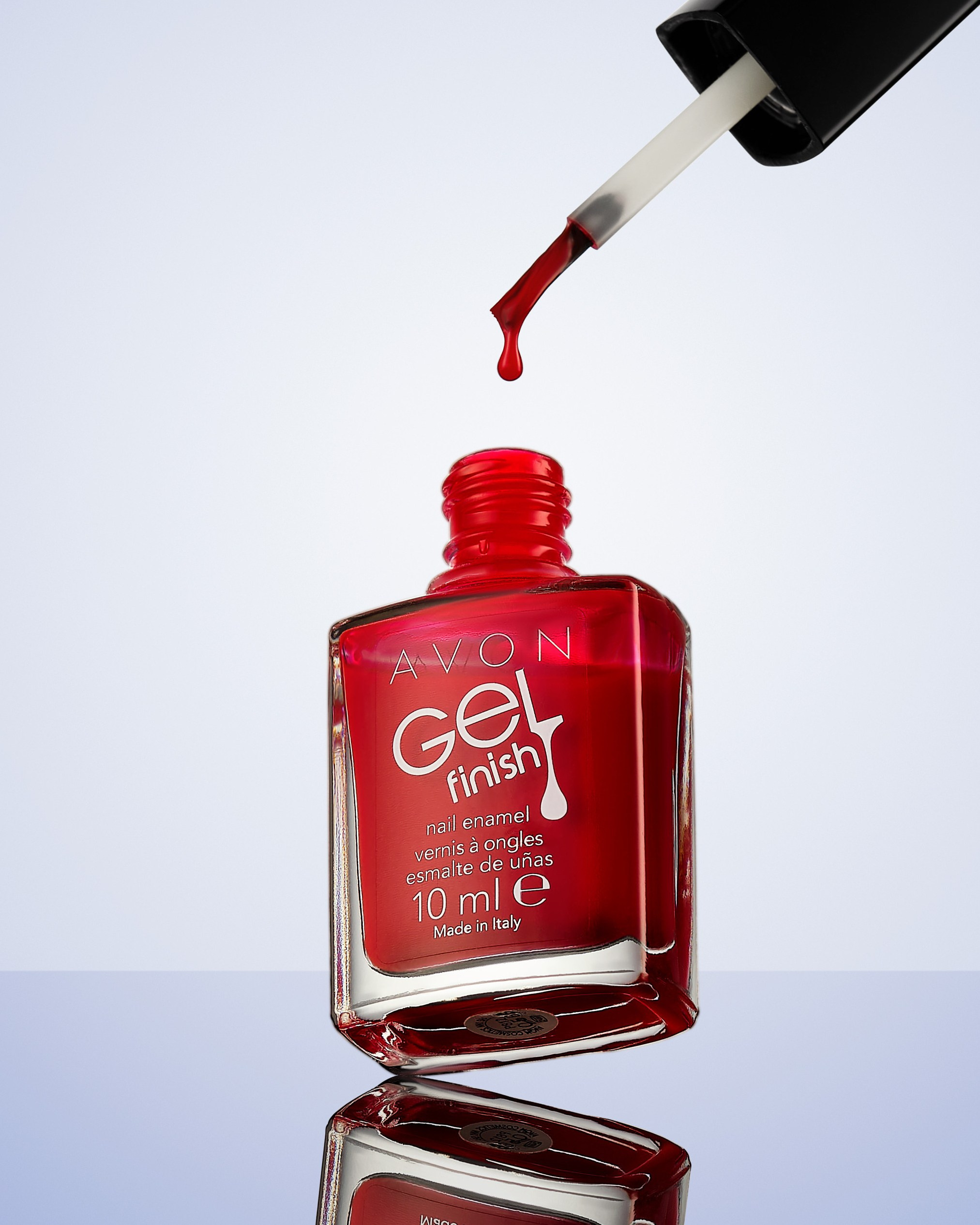 Лак для ногтей с кисточкой и каплей лака, падающей в бутылочку