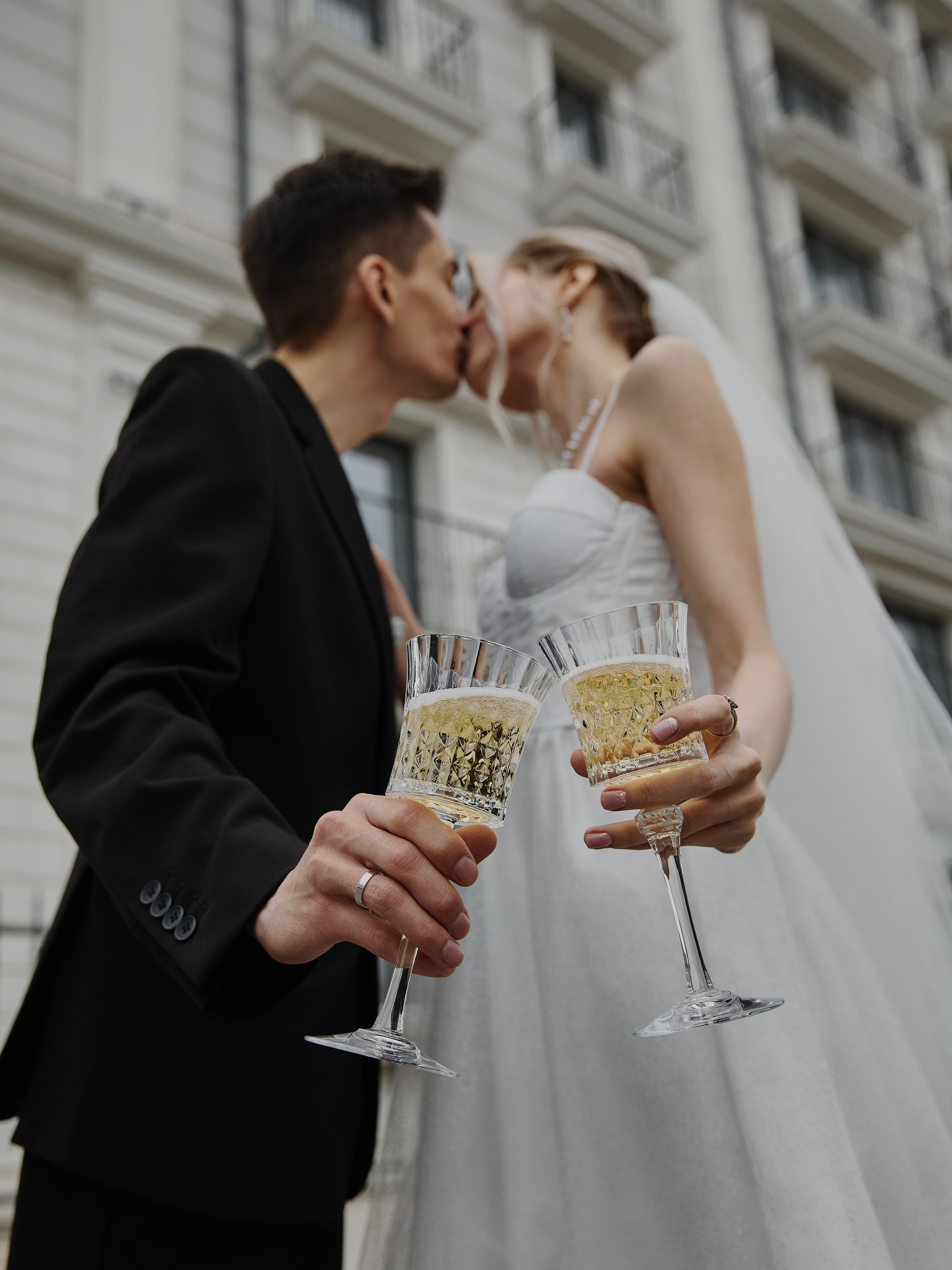 Бокалы с шампанским на фоне поцелуя молодоженов на белой набережной в Анапе