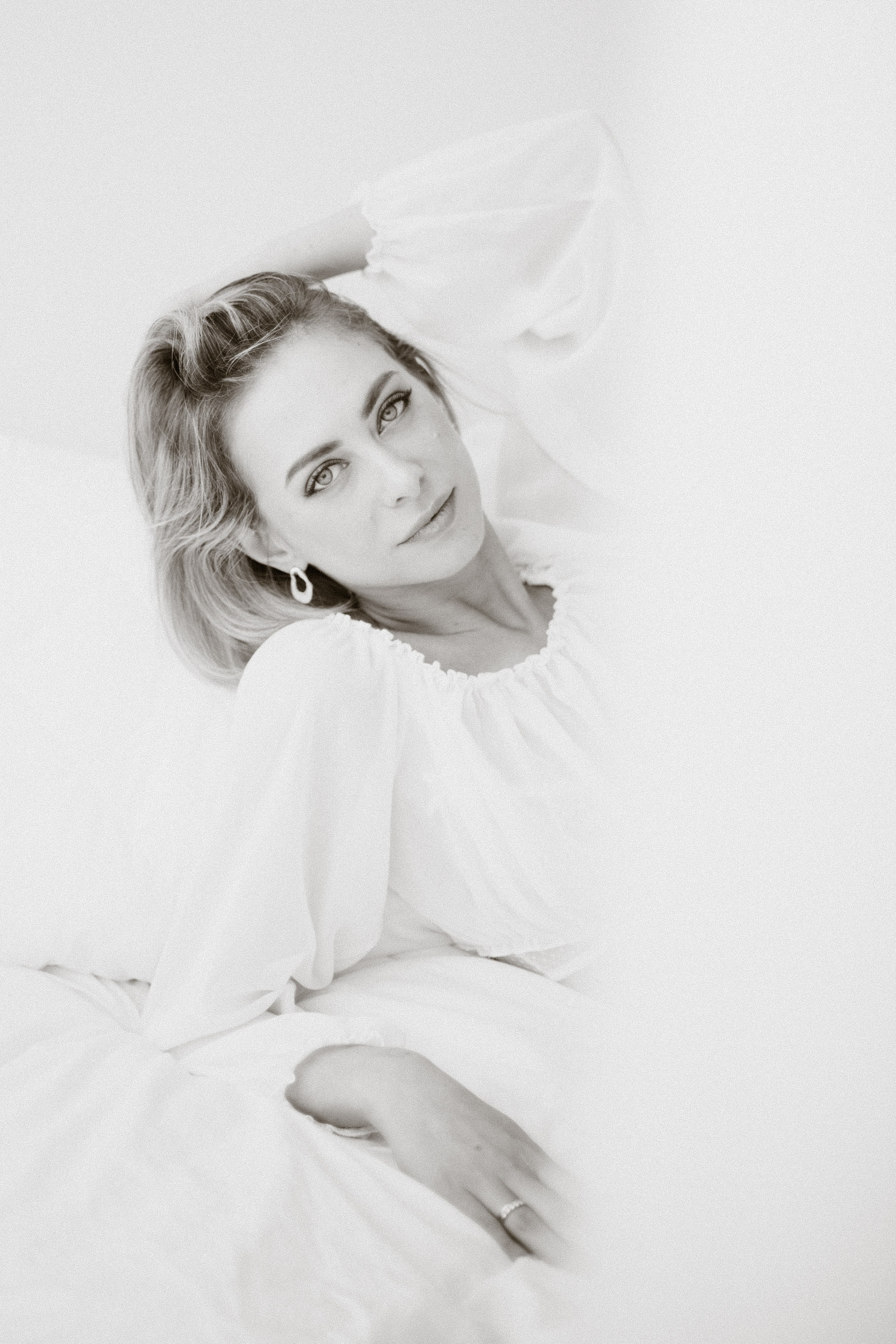 Фотосессия девушки в белом платье, фотосессия в светлых тонах, фотография девушки в студии, девушка лежит на кровати, черно-белое фото девушки