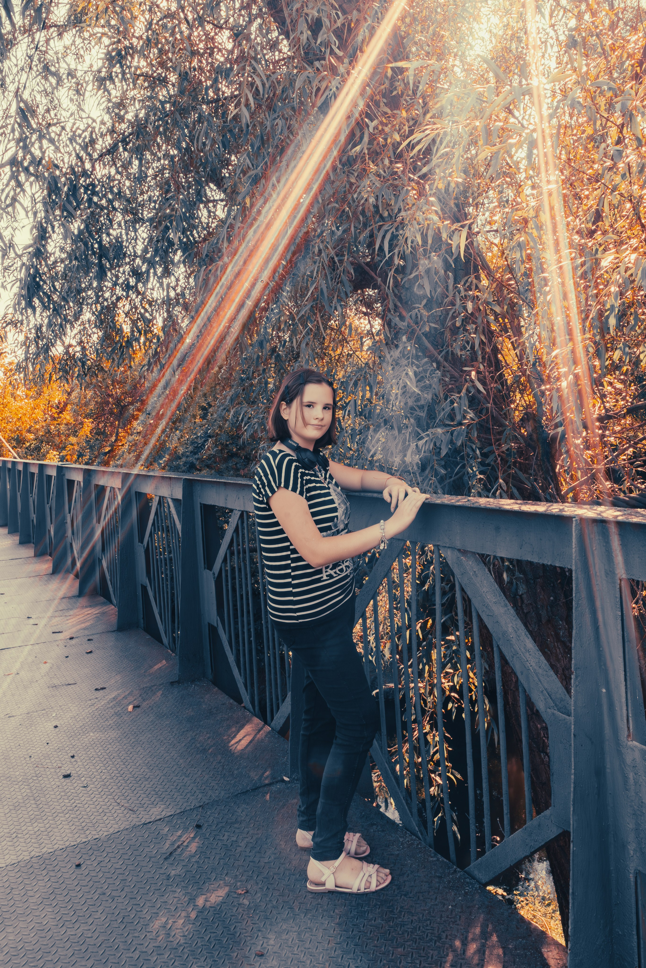 Девочка стоит на мосту и держится за металлические перила