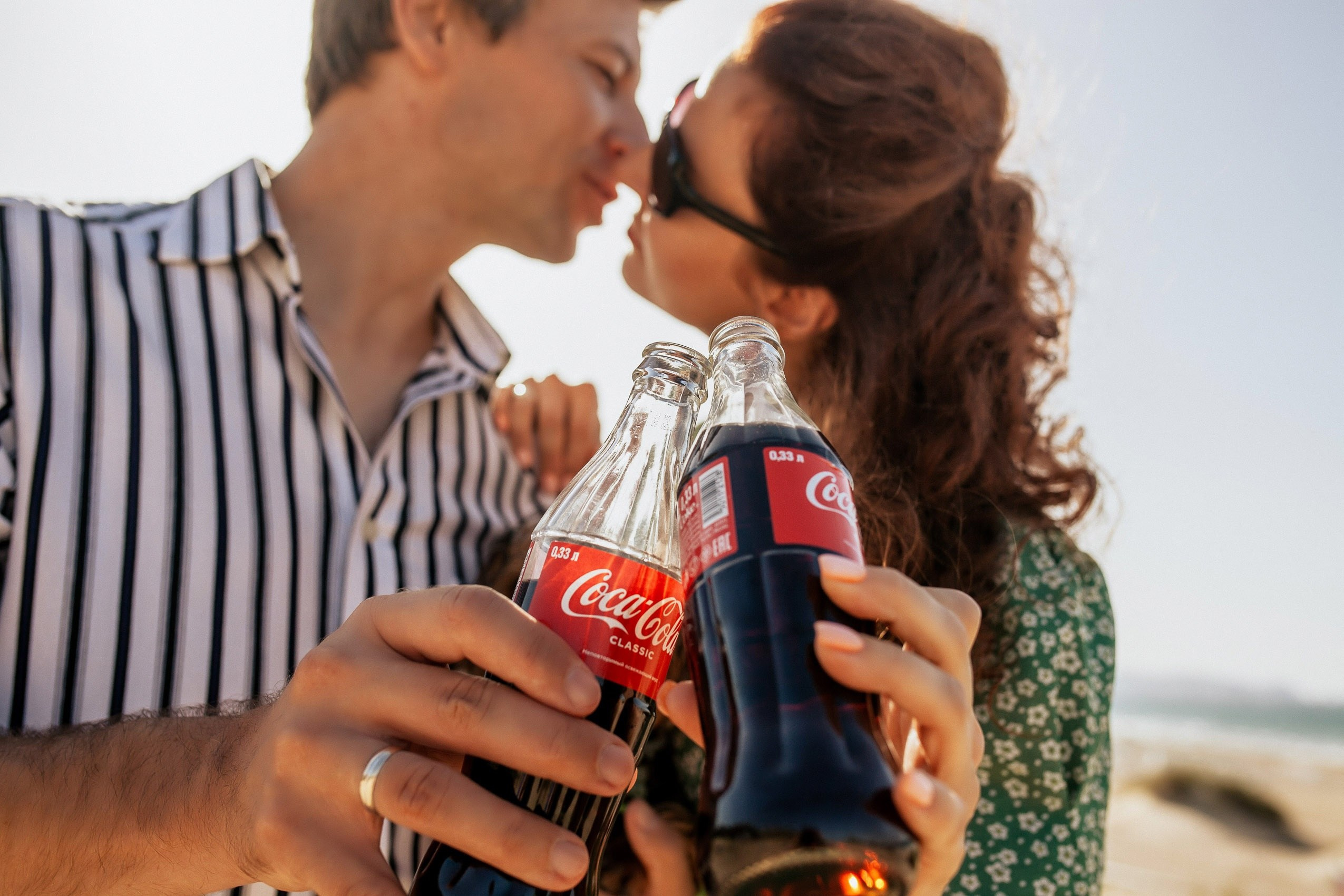 Необычная романтическая съемка с напитком кола кола на берегу моря.