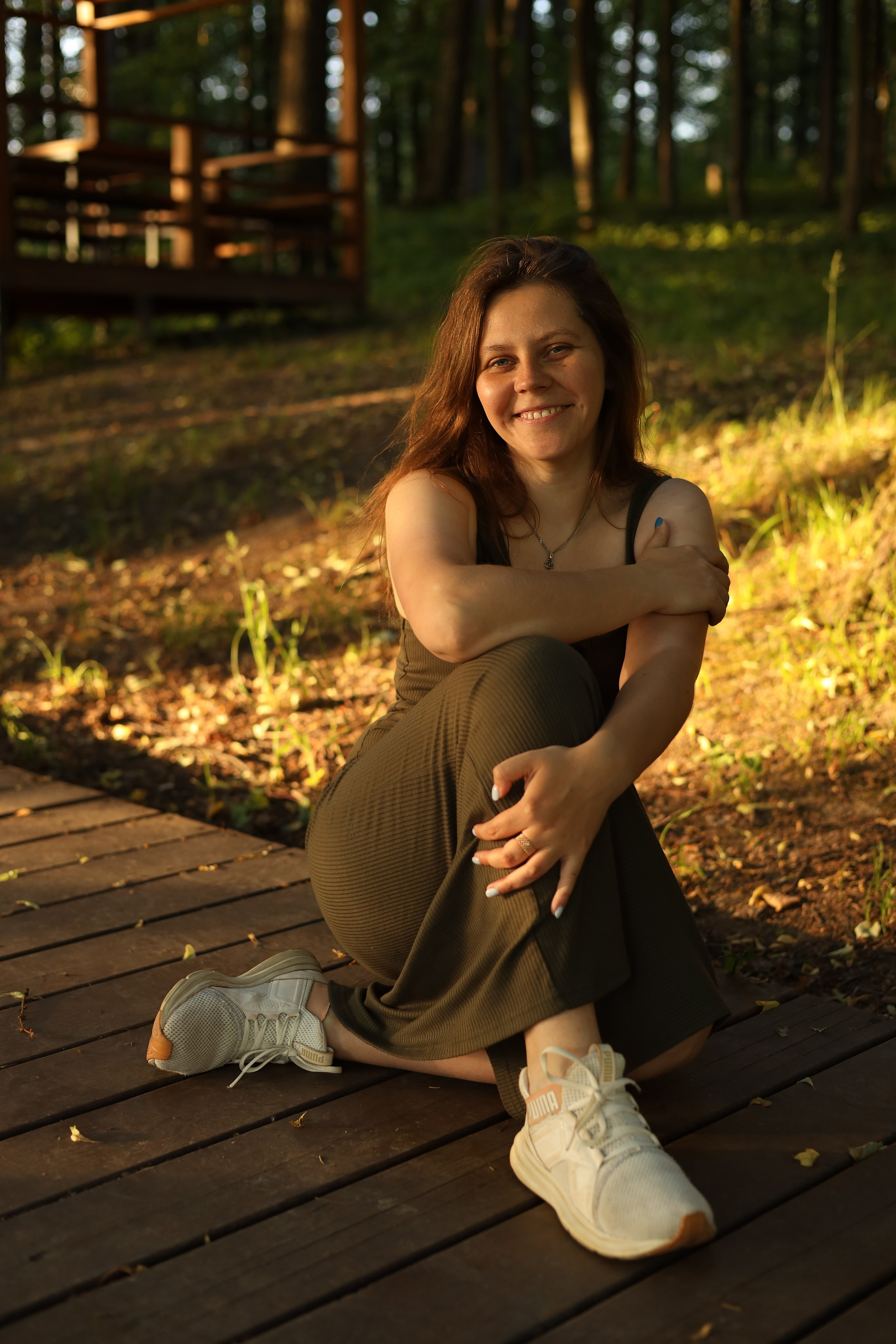 летом в парке девушка сидит улыбается на фотосессии на природе 