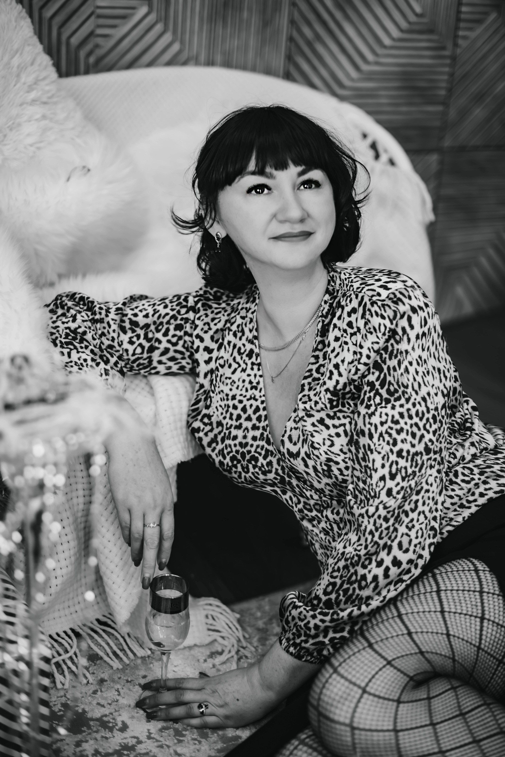 На фото  портрет девушки с подарком сидит около дивана в блузке.