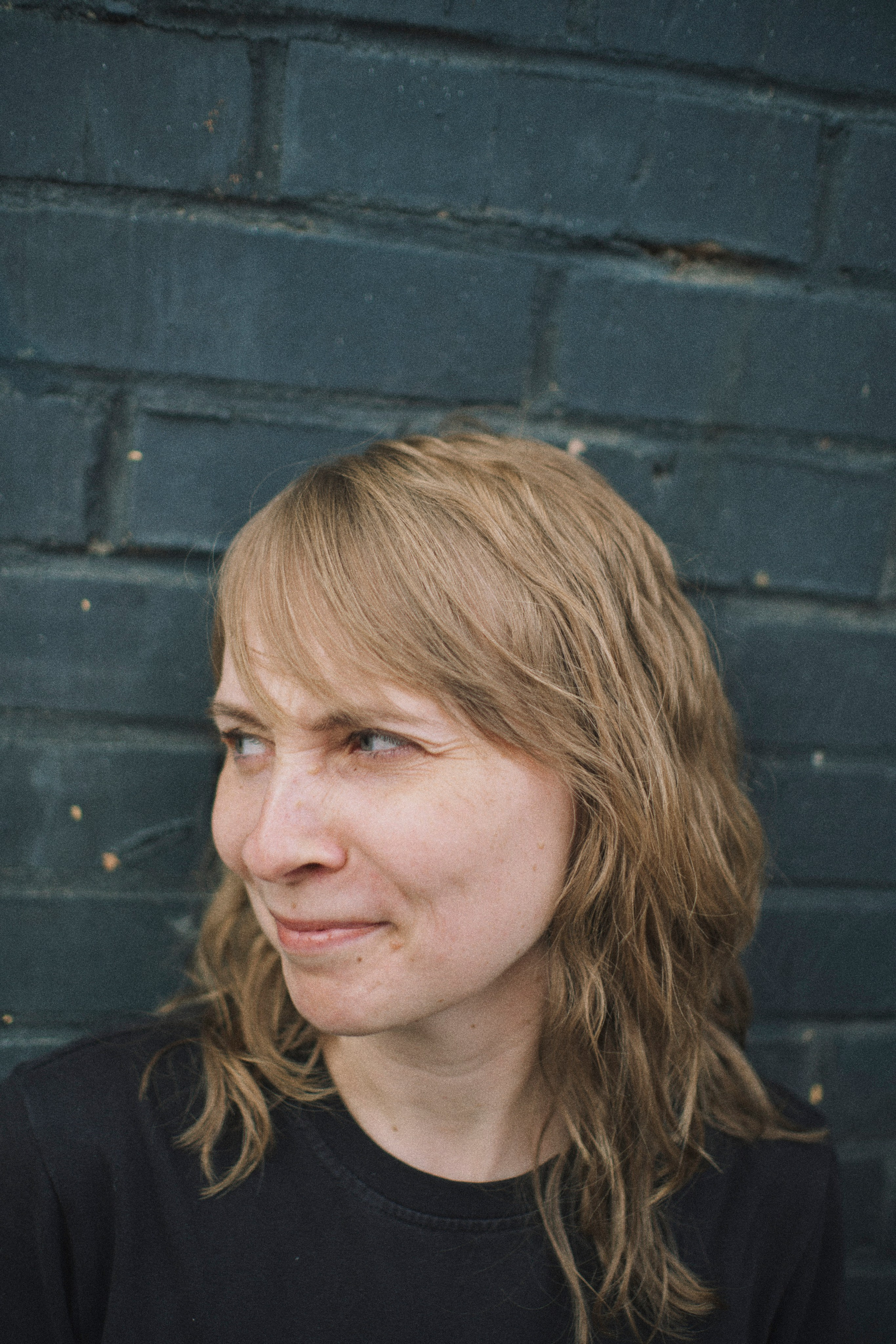 Женщина смеется на фоне стены