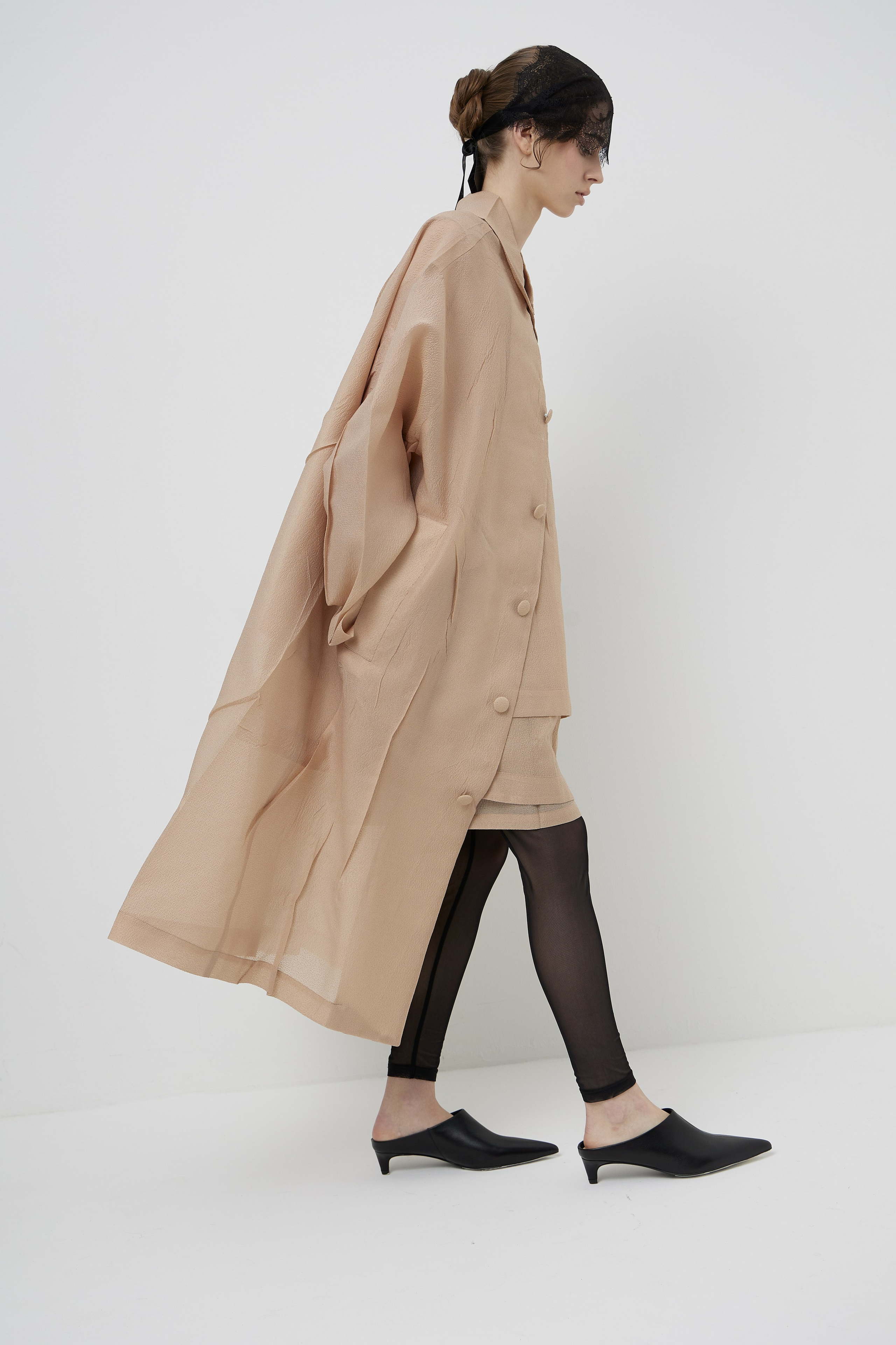 Side profile fashion lookbook photograph of model walking in minimalist designer coat created for fashion brand campaign and ecommerce photography in Sydney studio