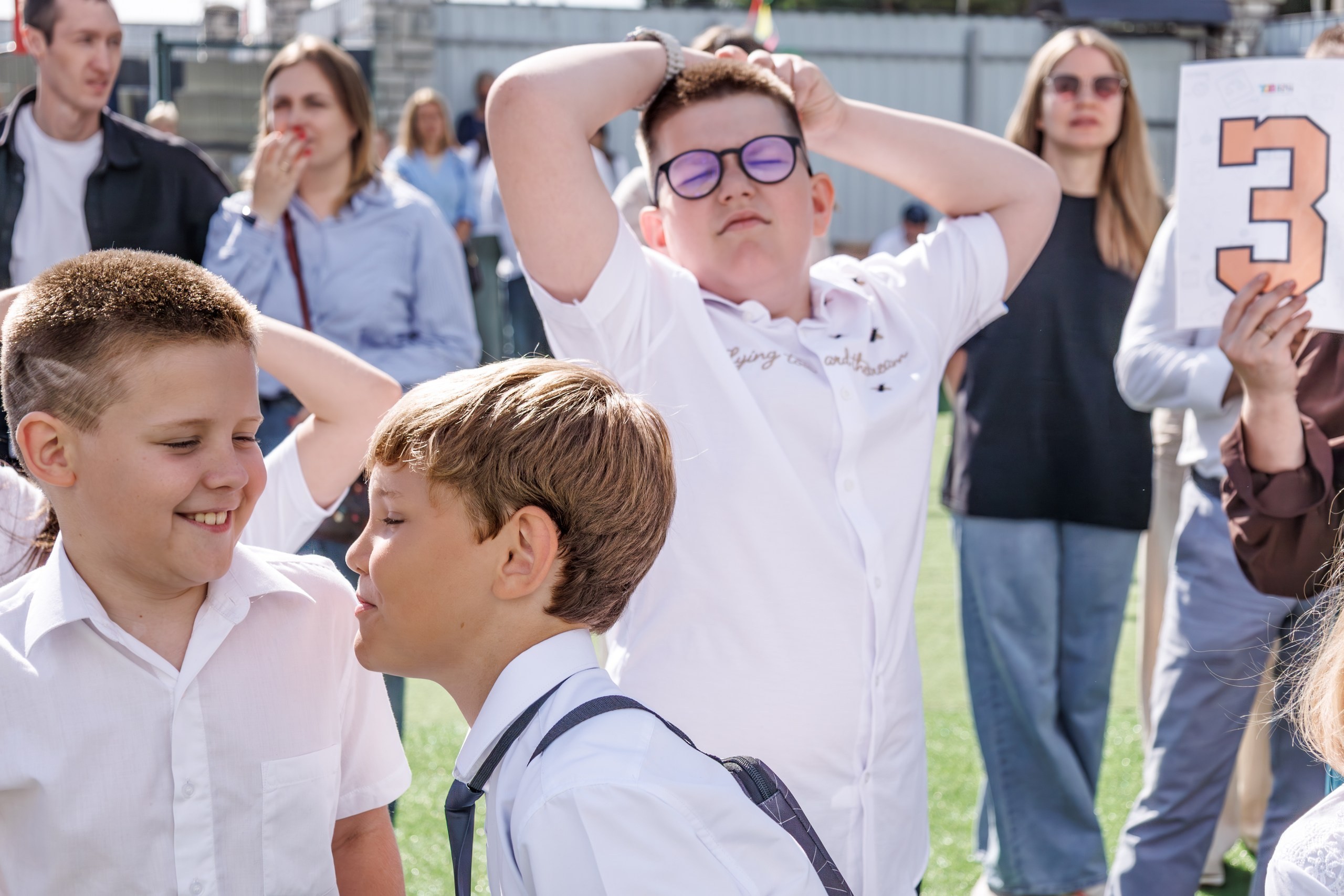 Линейка 1 сентября в школе - дети с букетами, радостные родители и учителя; дети обнимаются, радуются встрече с друзьями после каникул