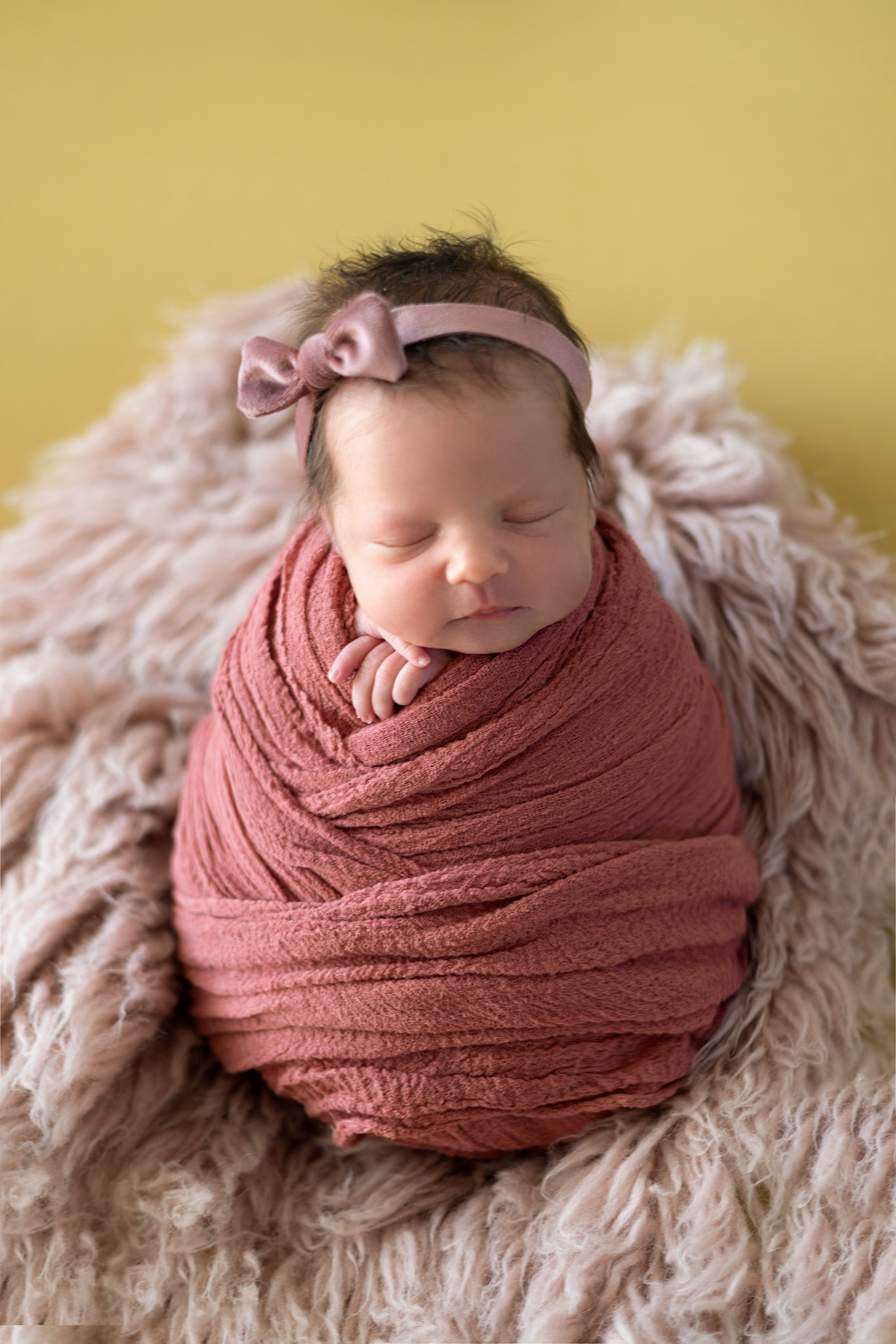 новорожденная малышка в позе стоячий кокон сладко спит с бантом