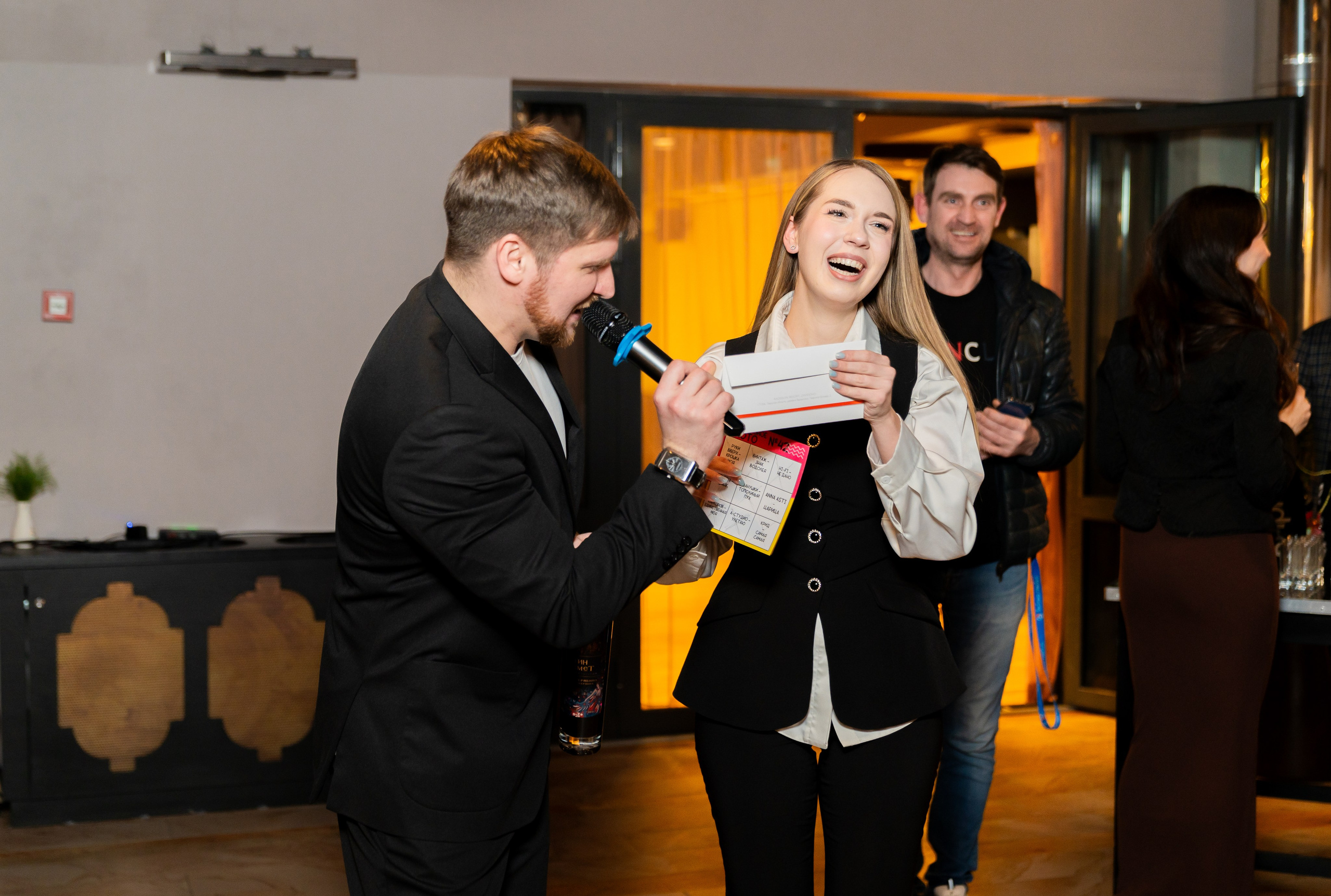 Смеющаяся девушка получает приз на розыгрыше в Radisson Sonya. Ведущий с микрофоном. Фотография Евгения Мальцева.